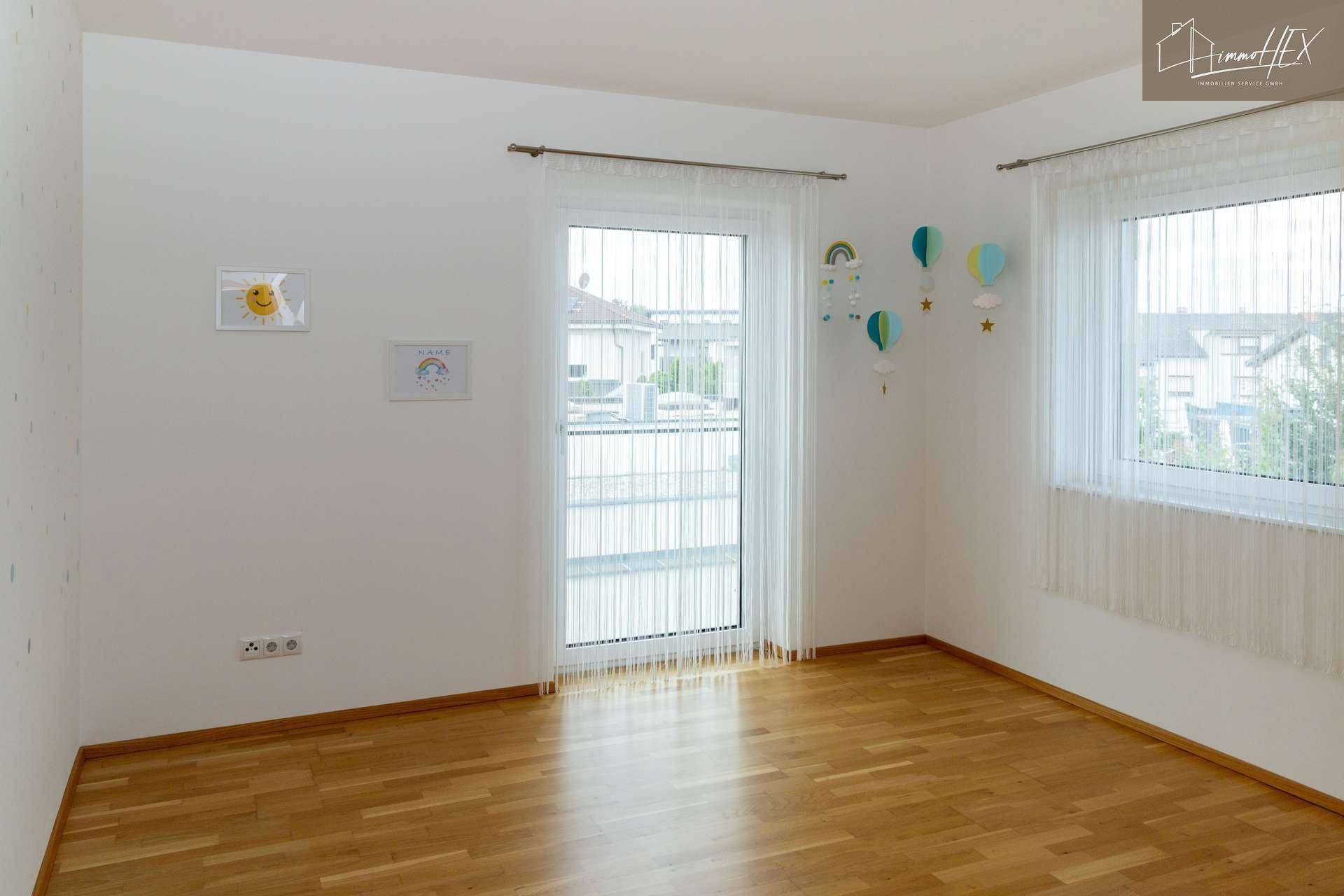 Geräumiges Kinderzimmer mit Holzboden und Blick auf die umliegenden Häuser.
