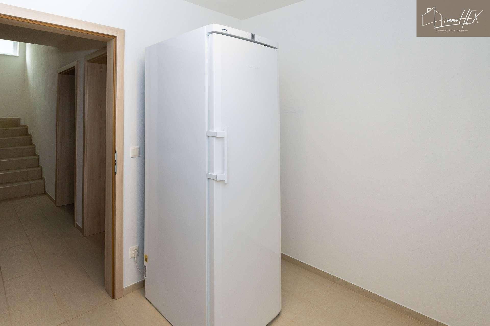 Heller Flur mit großem Standkühlschrank und Zugang zu weiteren Räumen.