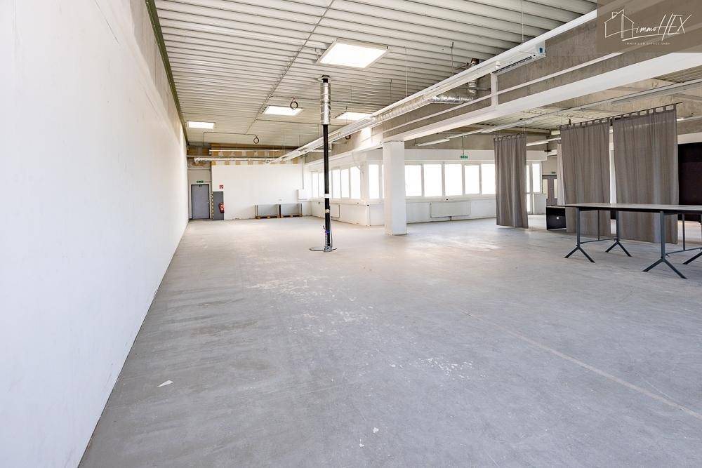 Großer, leerer Büroraum mit Betonboden und hohen Decken, bereit für die individuelle Gestaltung.