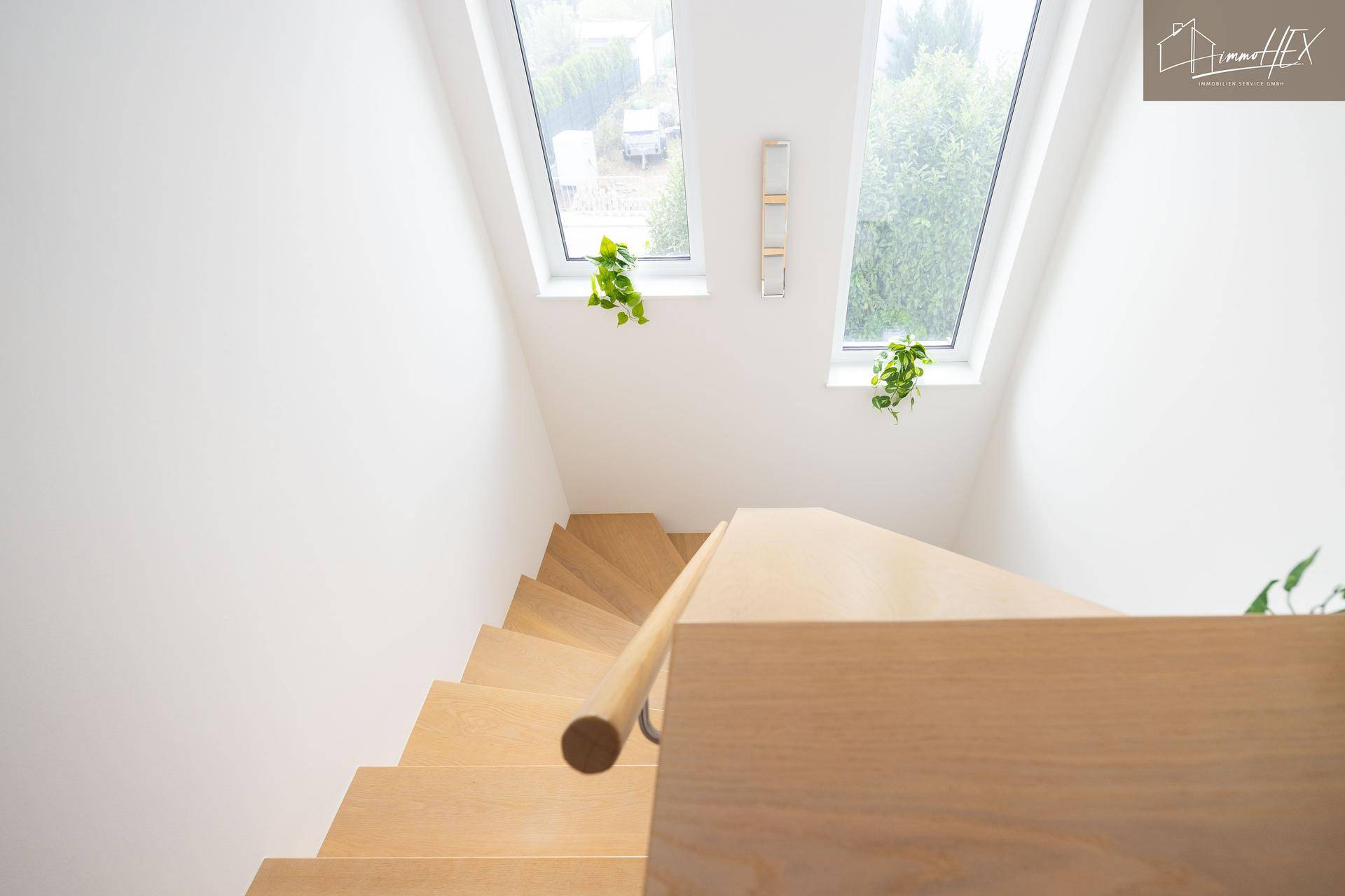 Heller Treppenaufgang mit Holzstufen und Dachfenstern, die viel Licht spenden.