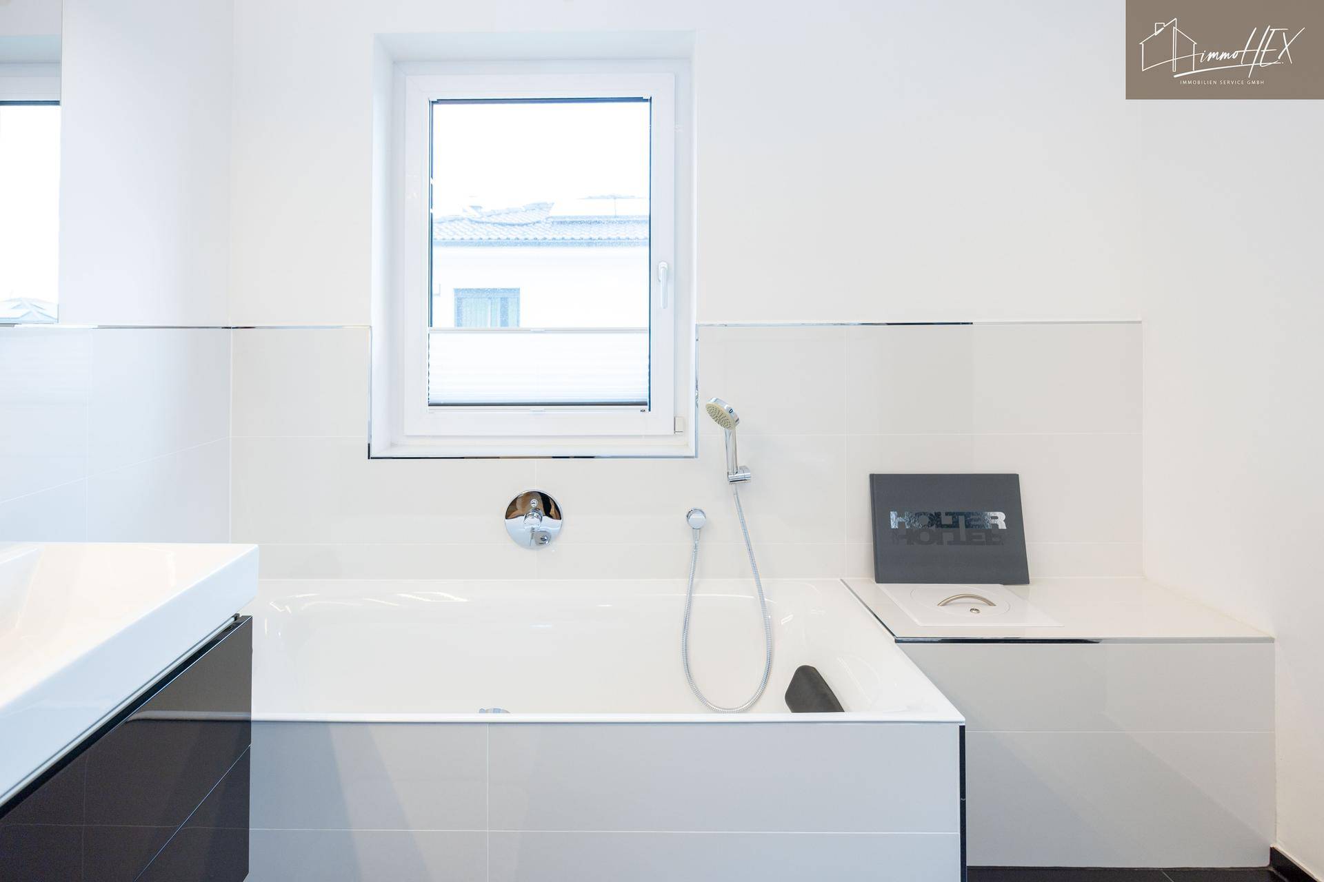 Badewanne mit Duschkopf und Fenster in einem modernen Badezimmer.