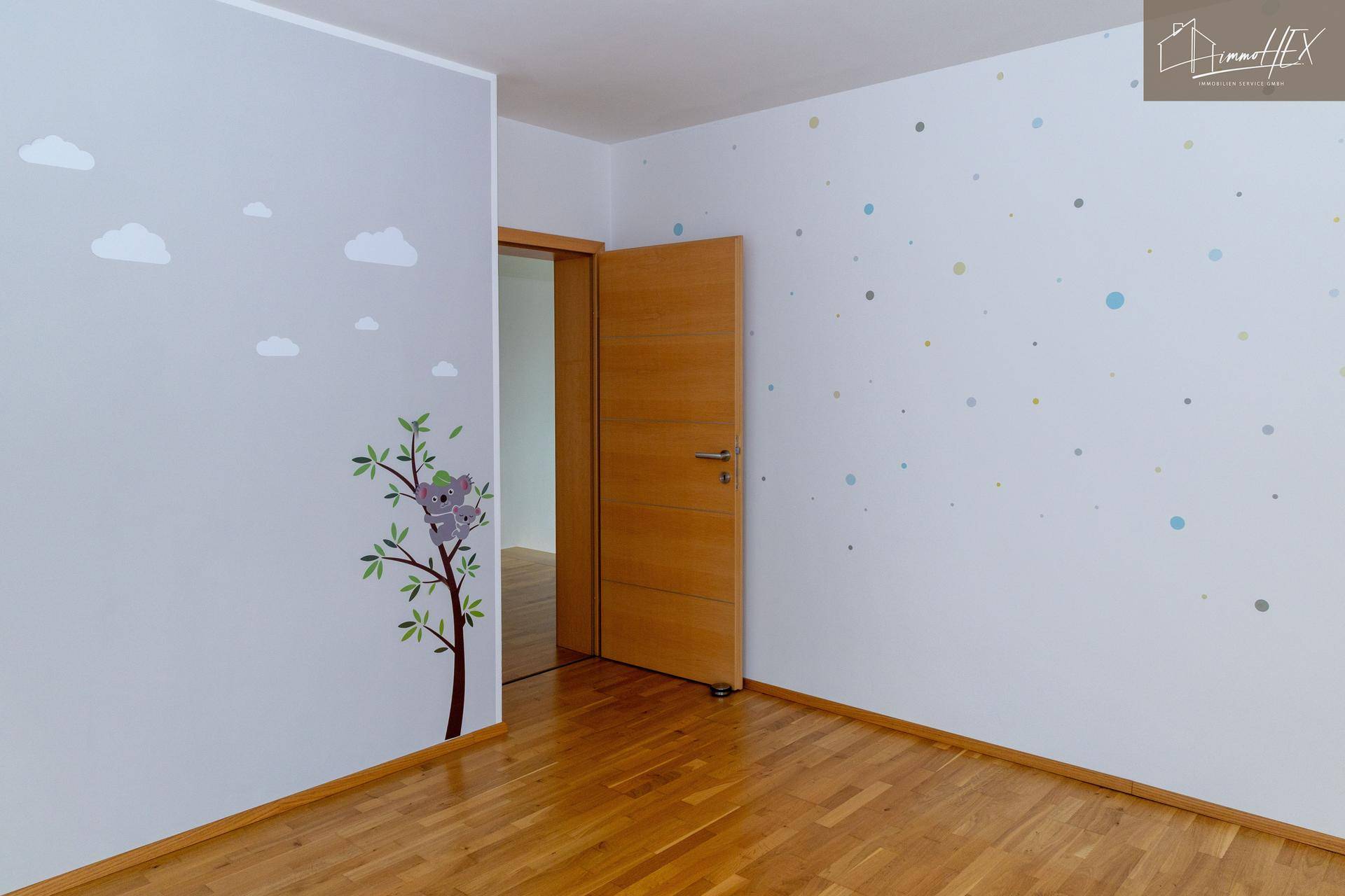 Kinderzimmer mit Holzboden und einer farbenfrohen Punkt-Wanddekoration, die eine fröhliche Atmosphäre schafft.