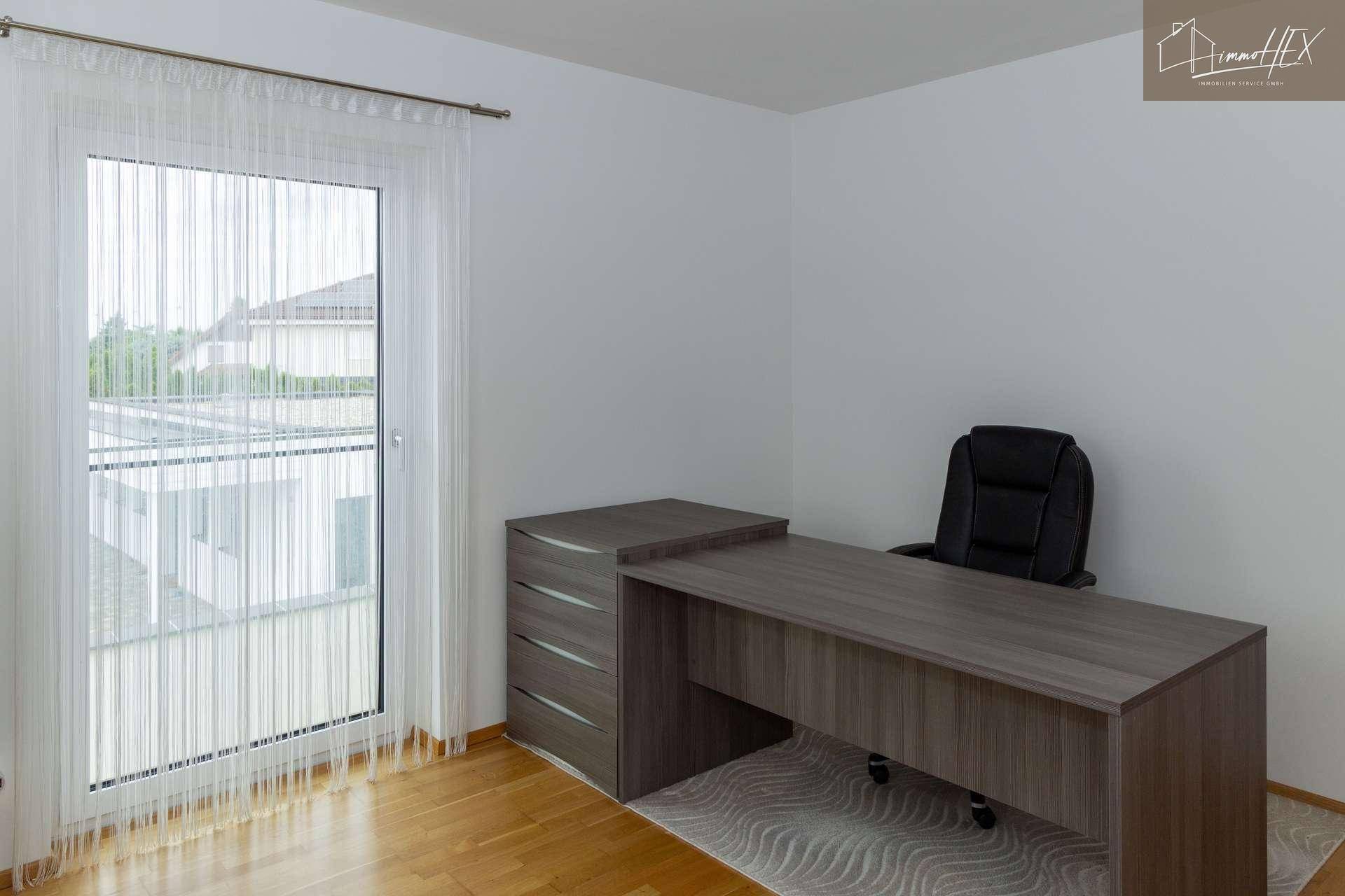 Büro mit Schreibtisch, Holzboden und Zugang zu einem Balkon oder Terrasse.