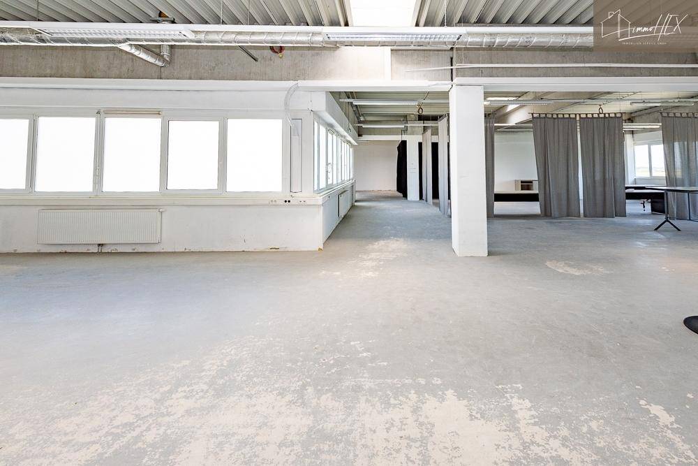 Weitläufiger Büroraum mit einer langen Fensterfront, die für viel Helligkeit sorgt.