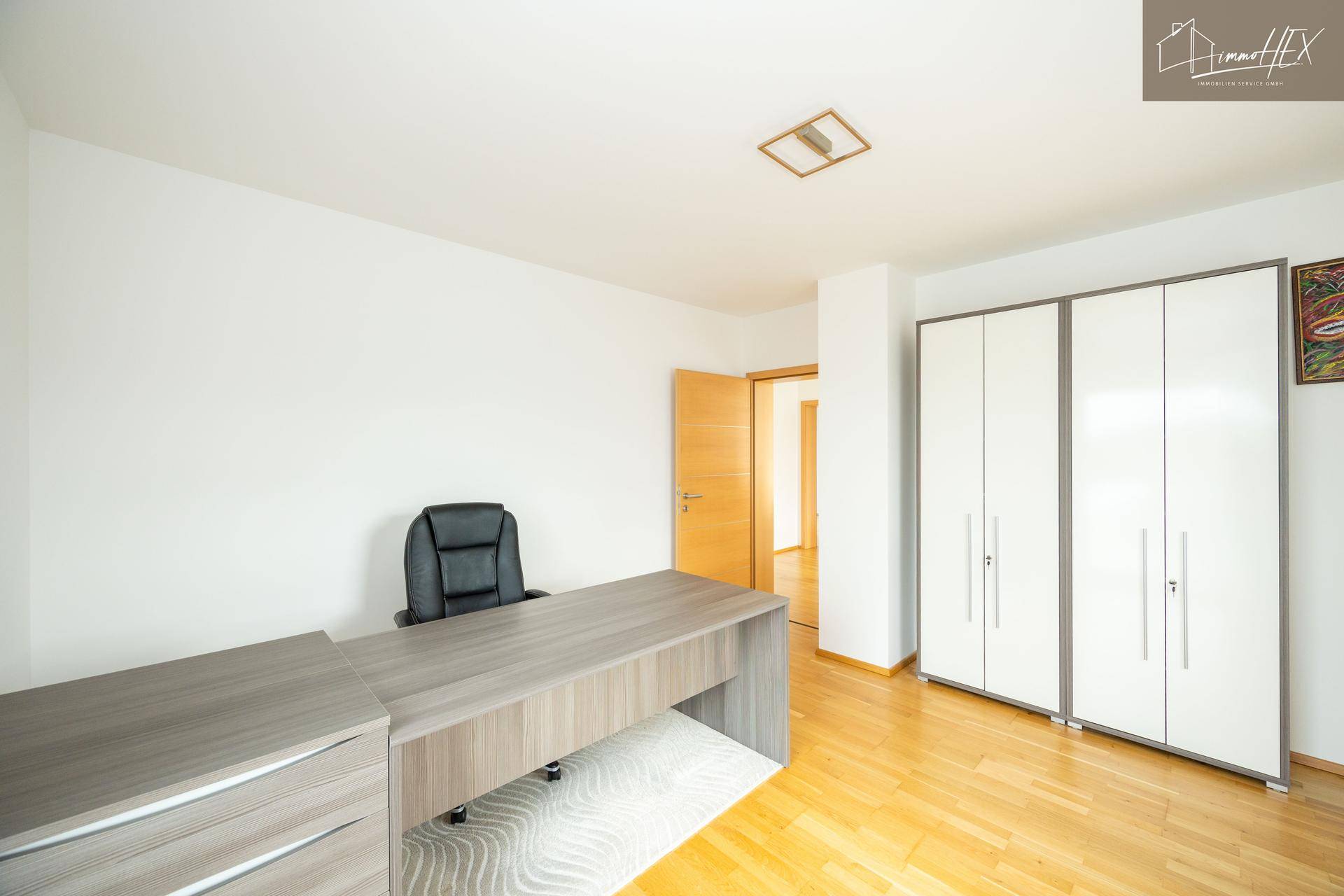 Modernes Büro mit Holzboden, Schreibtisch und weißem Kleiderschrank.