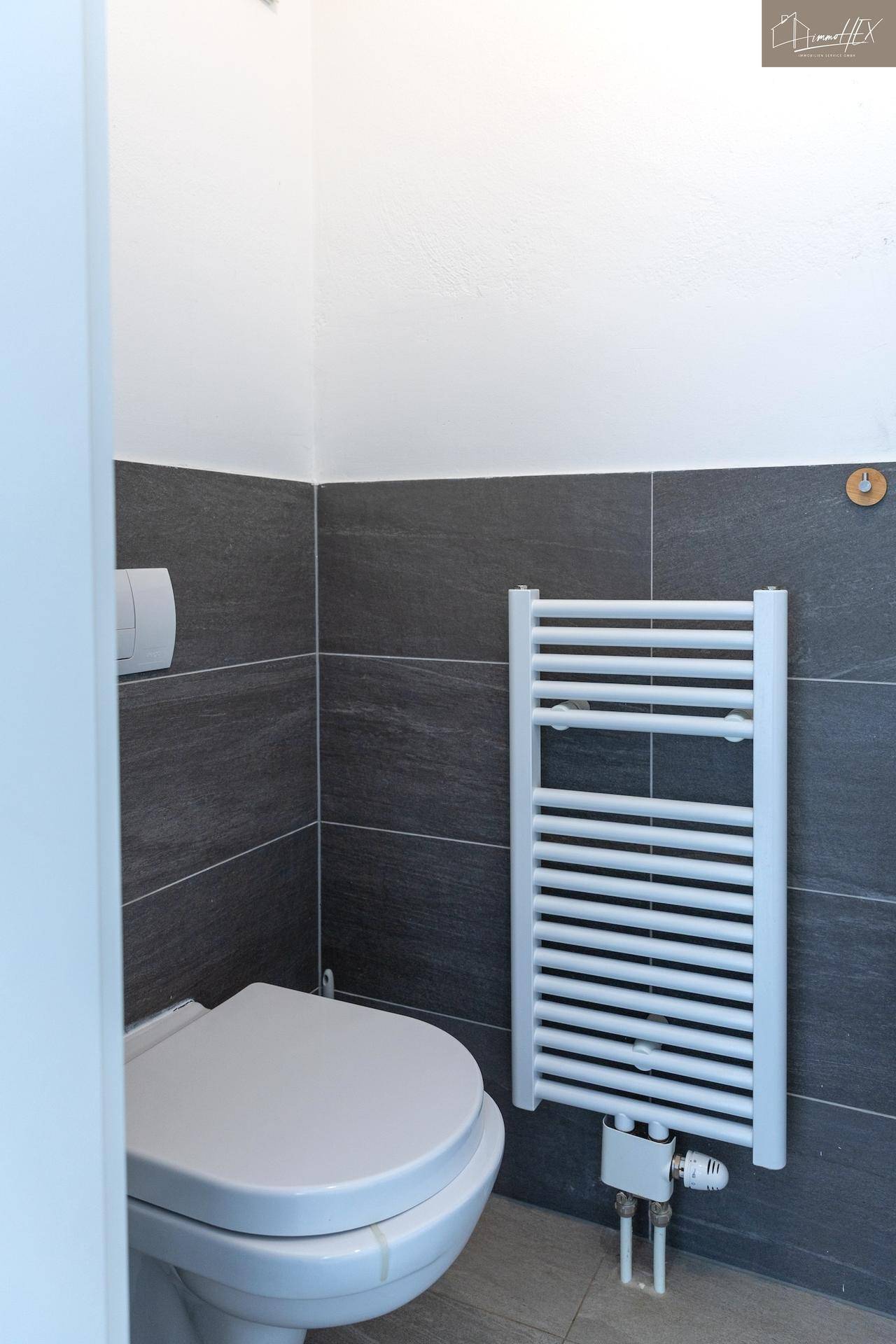 Modernes WC mit wandhängender Toilette und Heizkörper für Handtücher.