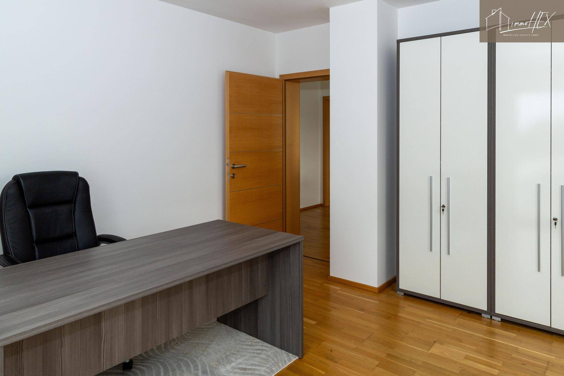 Modernes Büro mit Schreibtisch, Bürostuhl und Holztür.