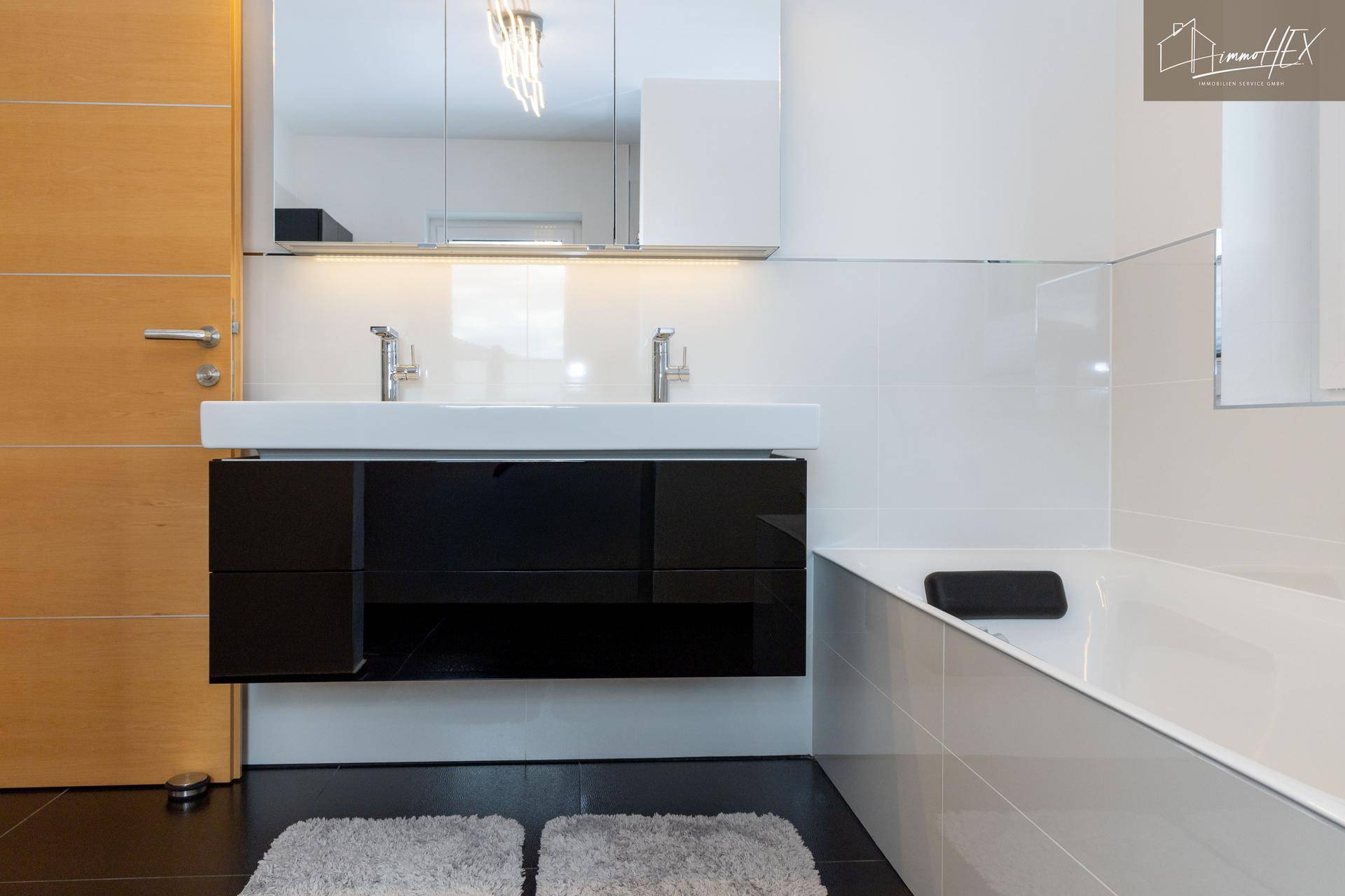 Doppelwaschbecken mit schwarzem Unterschrank und zwei modernen Armaturen im eleganten Badezimmer.