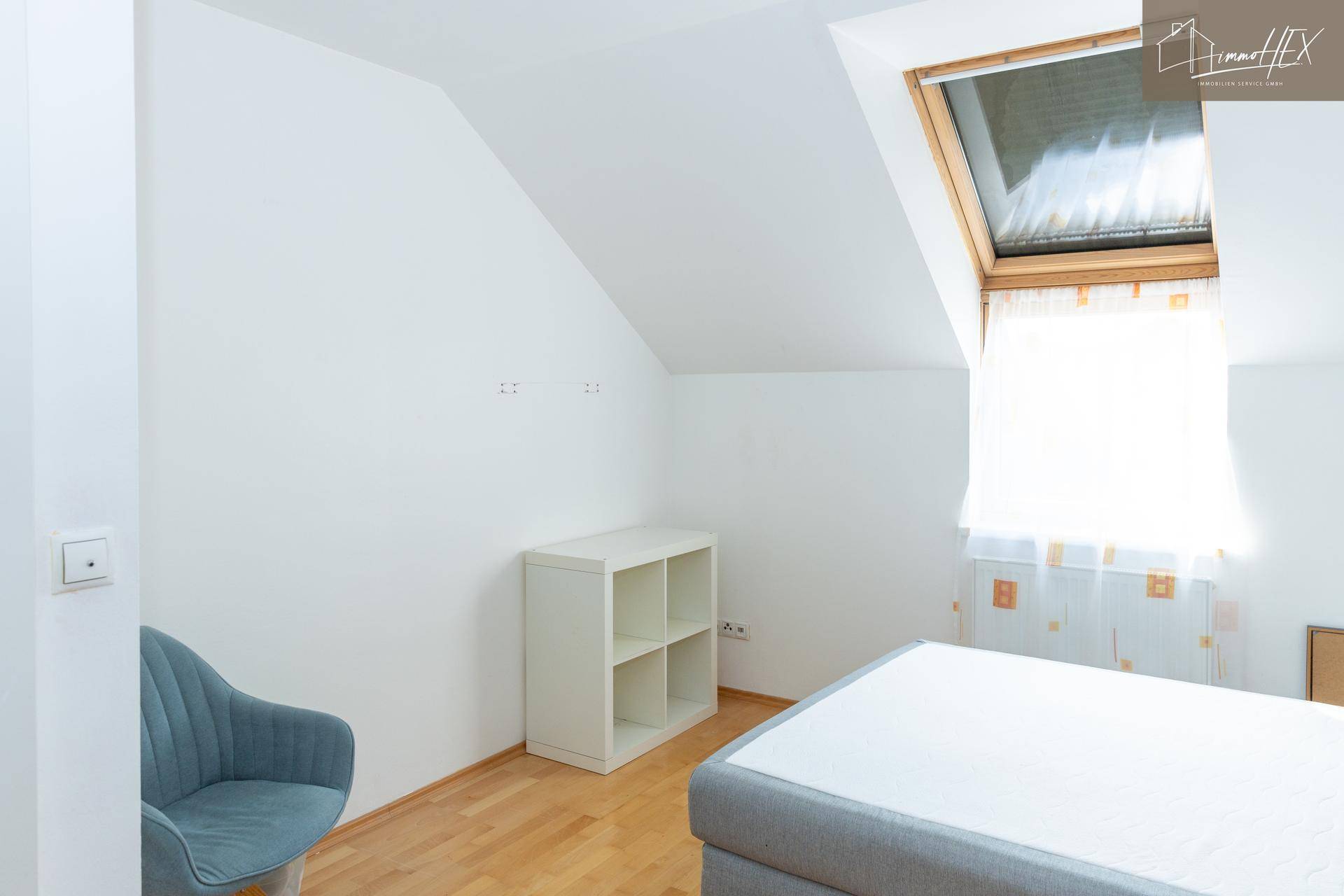 Gemütliches Schlafzimmer im Dachgeschoss mit Holzboden, Bett und Dachfenster.