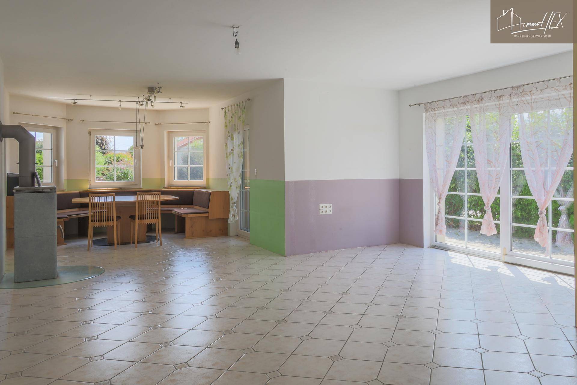 Geräumiger Wohn-Essbereich mit Fliesenboden, Kaminofen und Zugang zur Terrasse oder Garten.