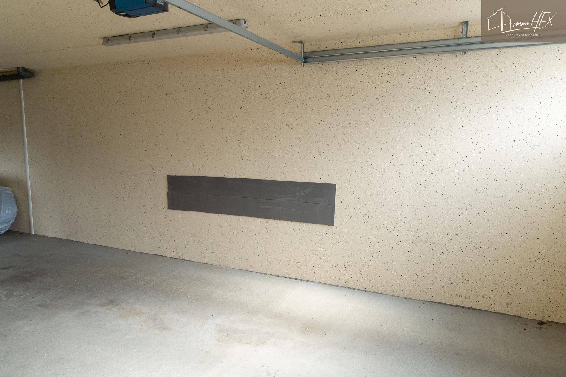 Innenansicht einer Garage mit strukturierten Wänden und Betonboden.