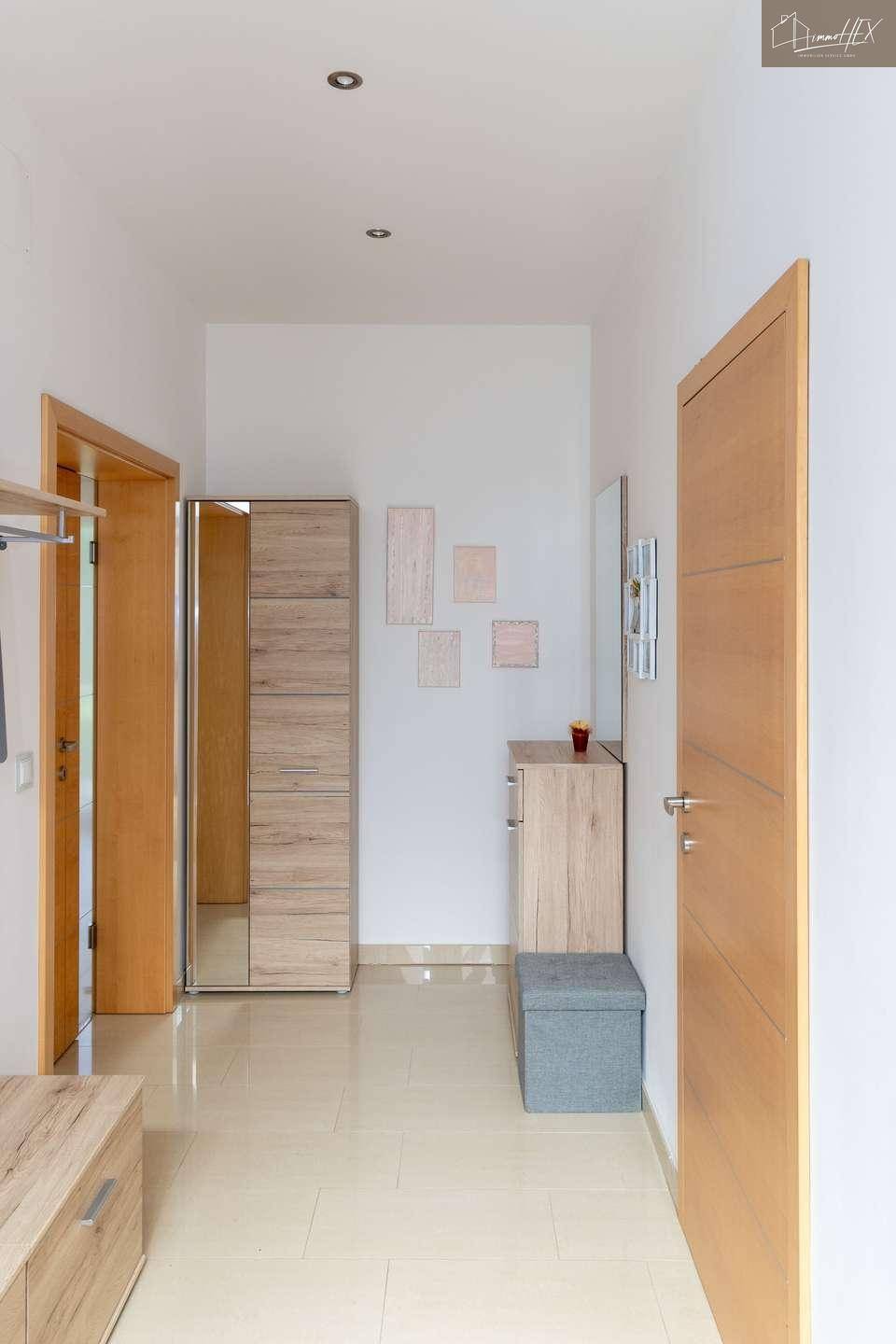 Heller Flur mit Fliesenboden und Holzmöbeln, der zu den Wohnbereichen führt.