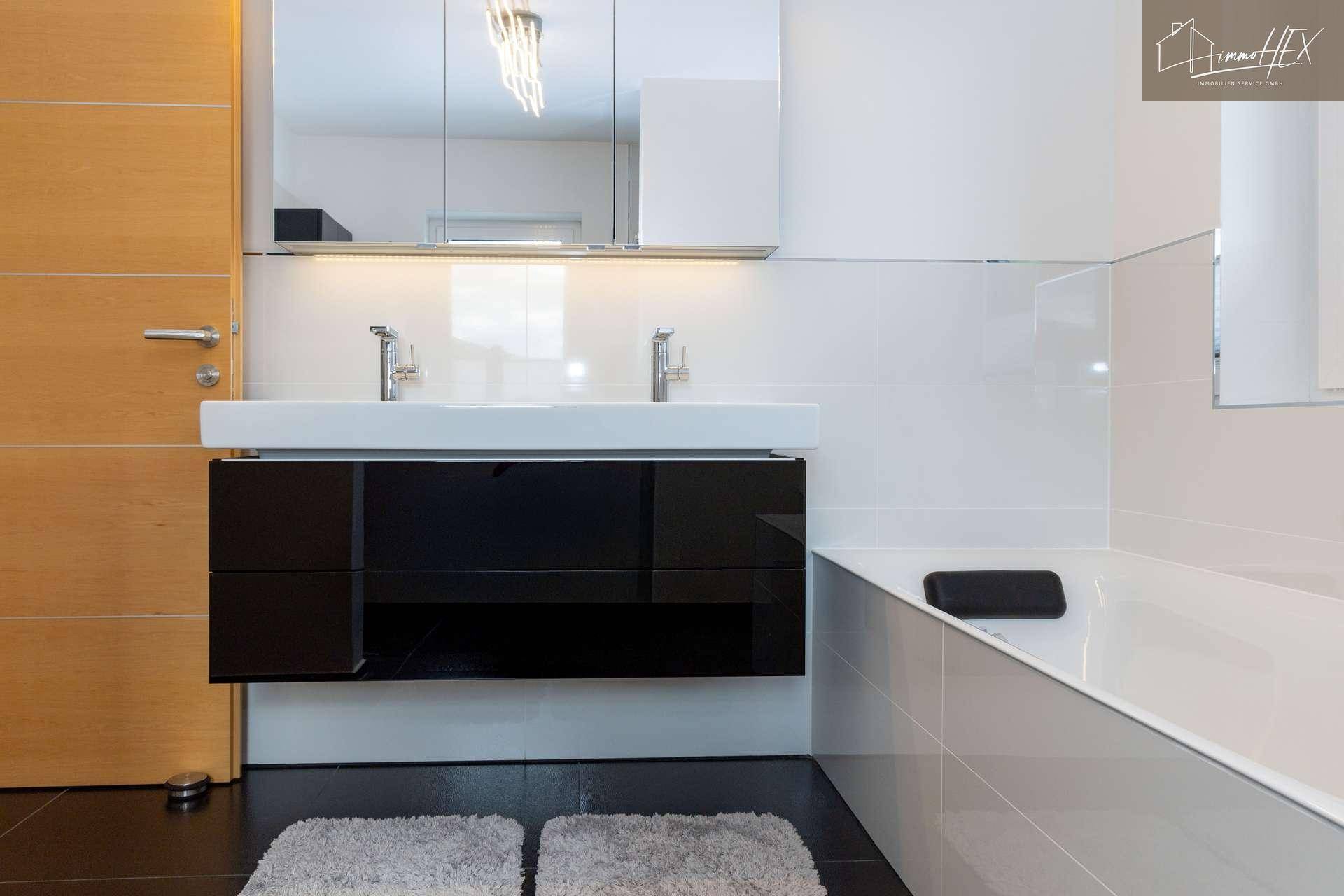 Doppelwaschbecken mit schwarzem Unterschrank und modernen Armaturen im Badezimmer.