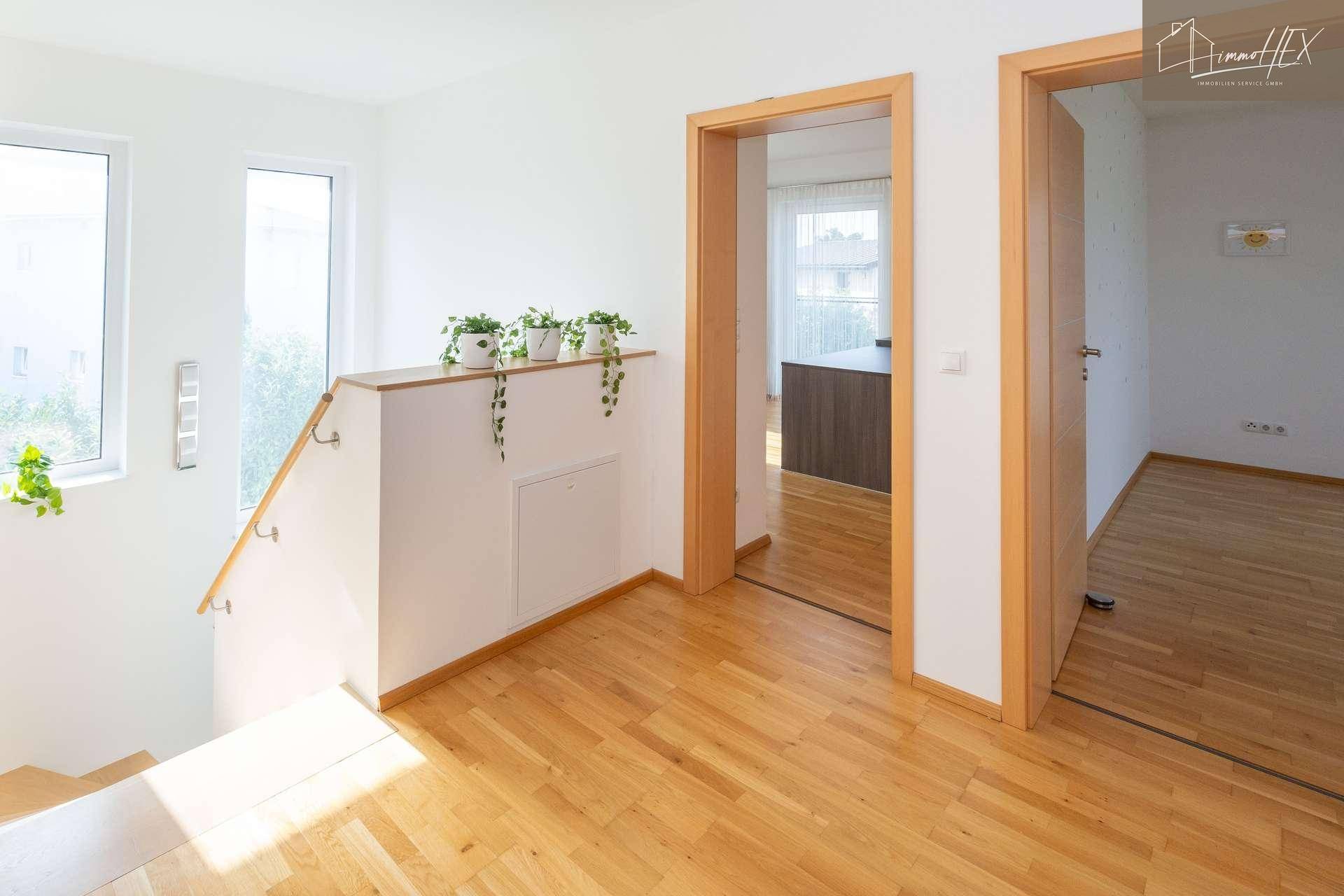 Lichtdurchfluteter Flur mit Holzboden und Zugang zu verschiedenen Räumen im Obergeschoss.