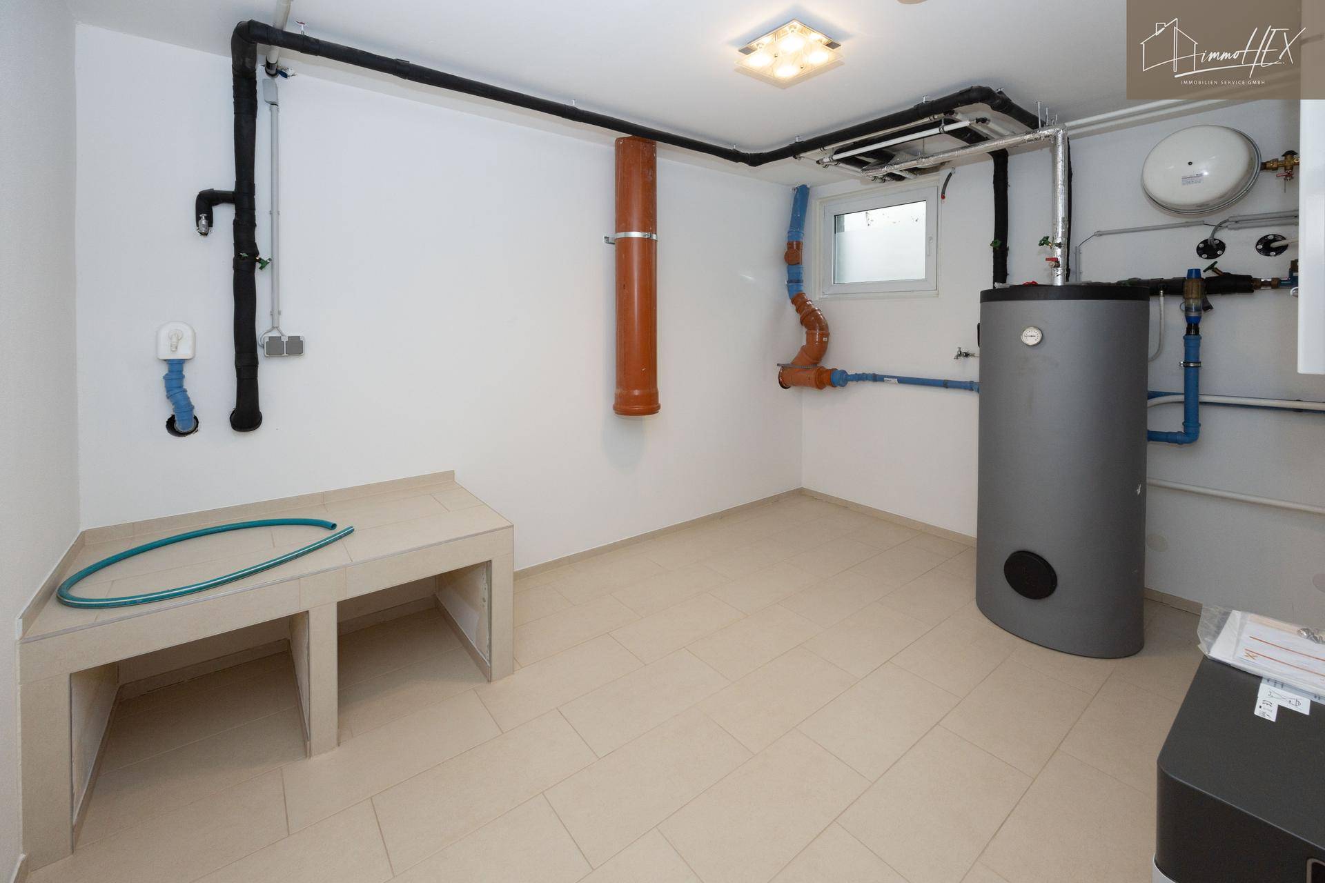 Geräumiger Technikraum mit Warmwasserspeicher und Arbeitsfläche, ideal für Haustechnik.