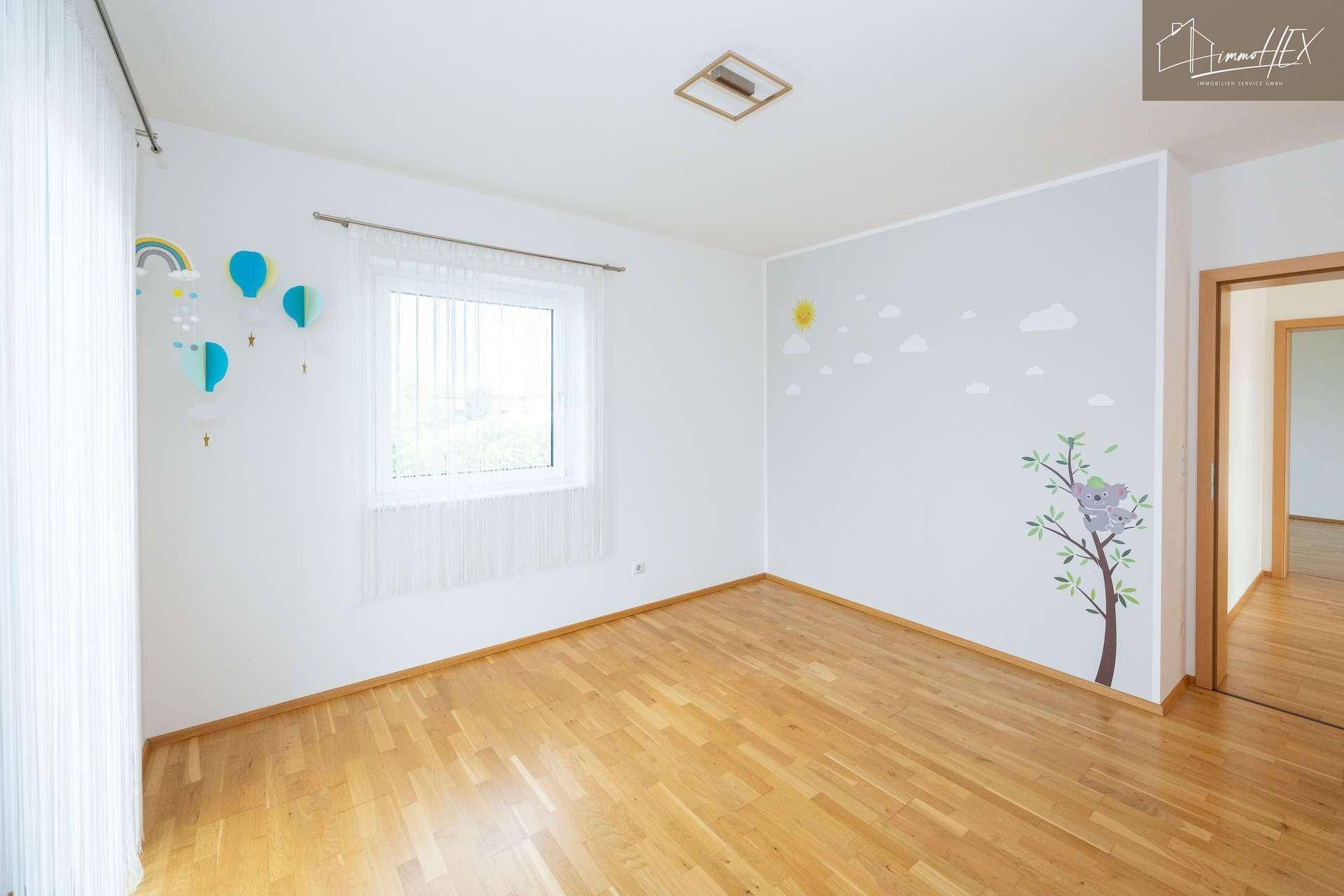 Helles Kinderzimmer mit Holzboden und verspielten Wanddekorationen.