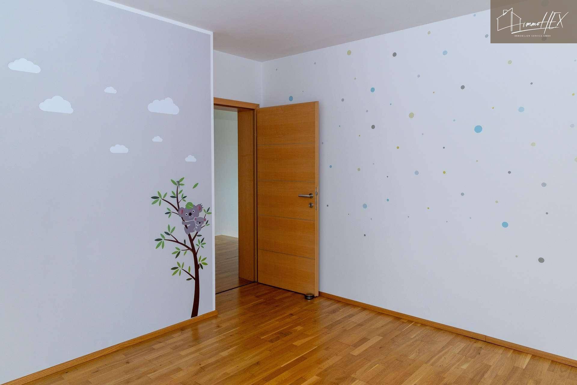 Kinderzimmer mit Holzboden, bunter Punktetapete und Holztür.