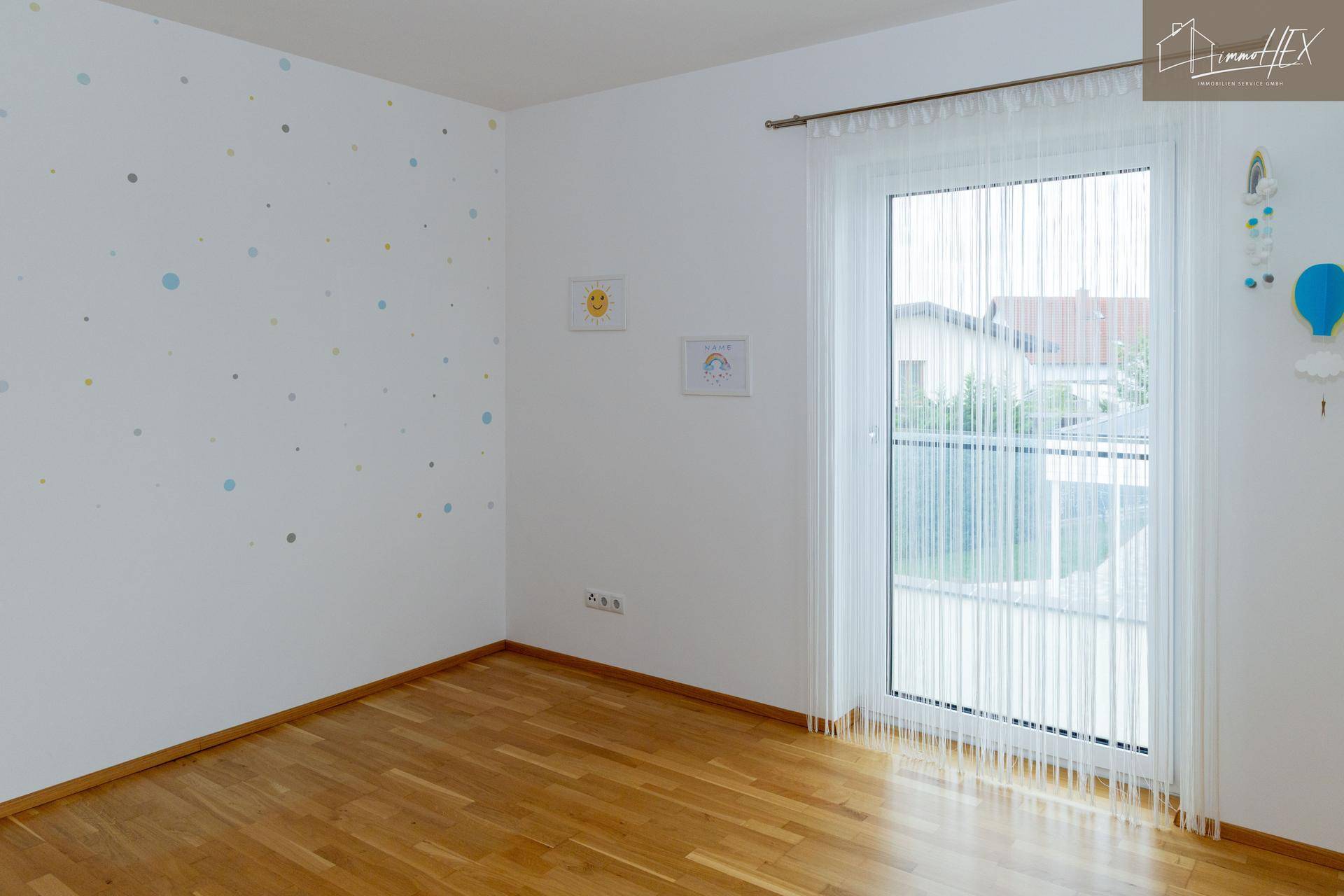 Freundliches Kinderzimmer mit Holzboden und Zugang zu einem Außenbereich.