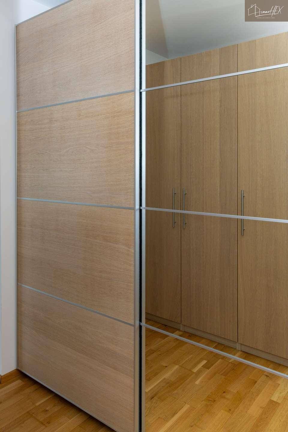 Detailansicht der modernen Einbauschränke aus Holz mit Spiegelfronten im Flurbereich.