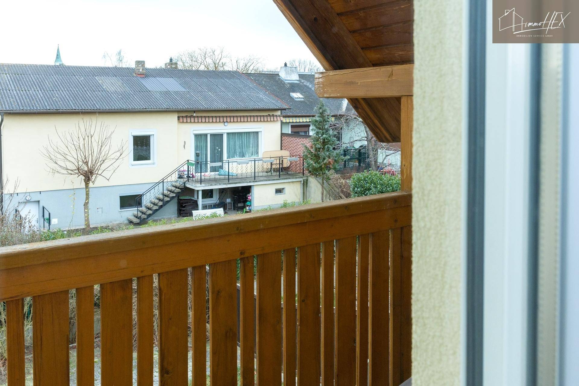 Blick vom Holzbalkon auf die umliegenden Häuser und den Gartenbereich.