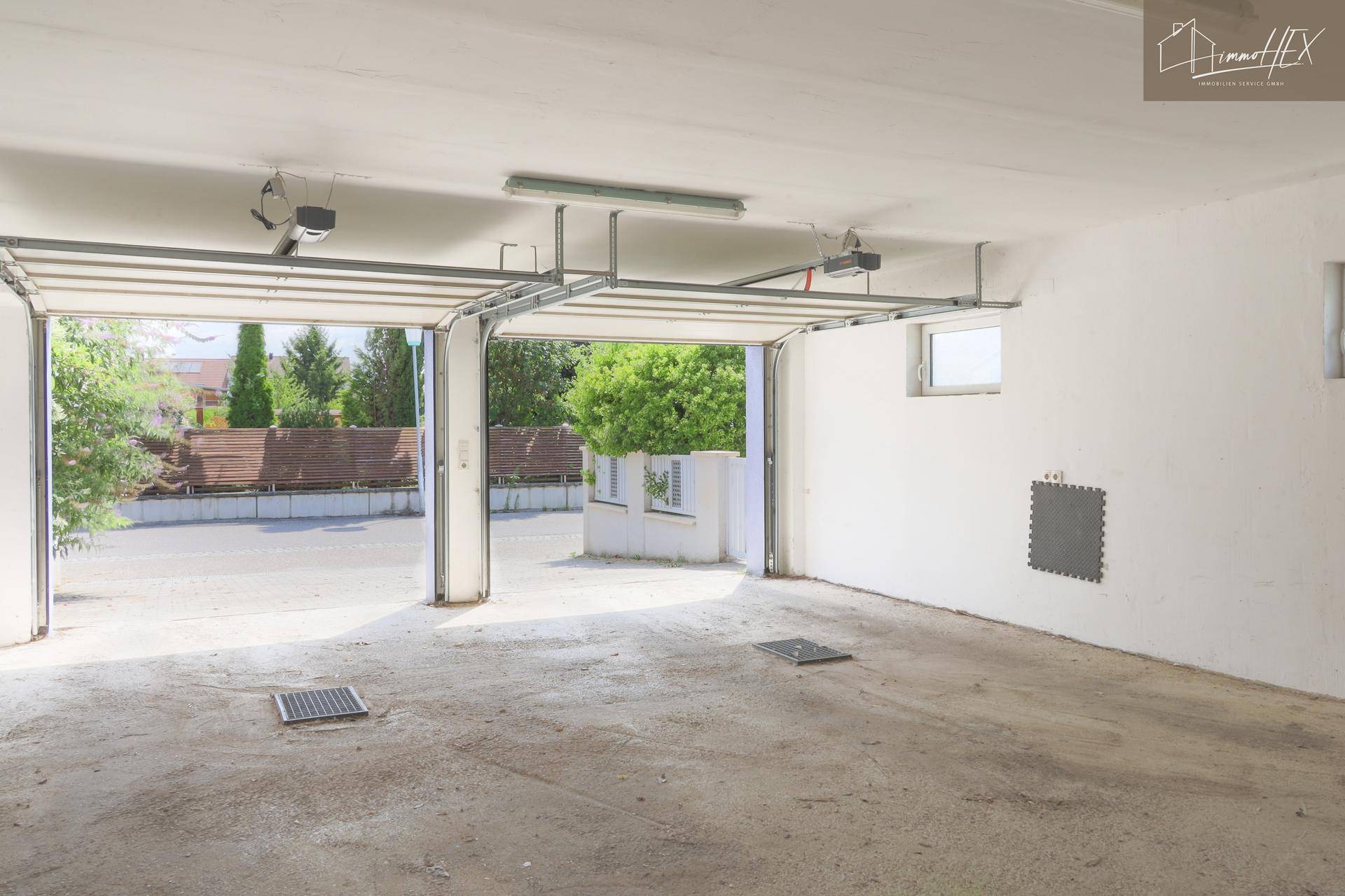Innenansicht der Doppelgarage mit Blick nach draußen, Betonboden und geöffneten Toren.