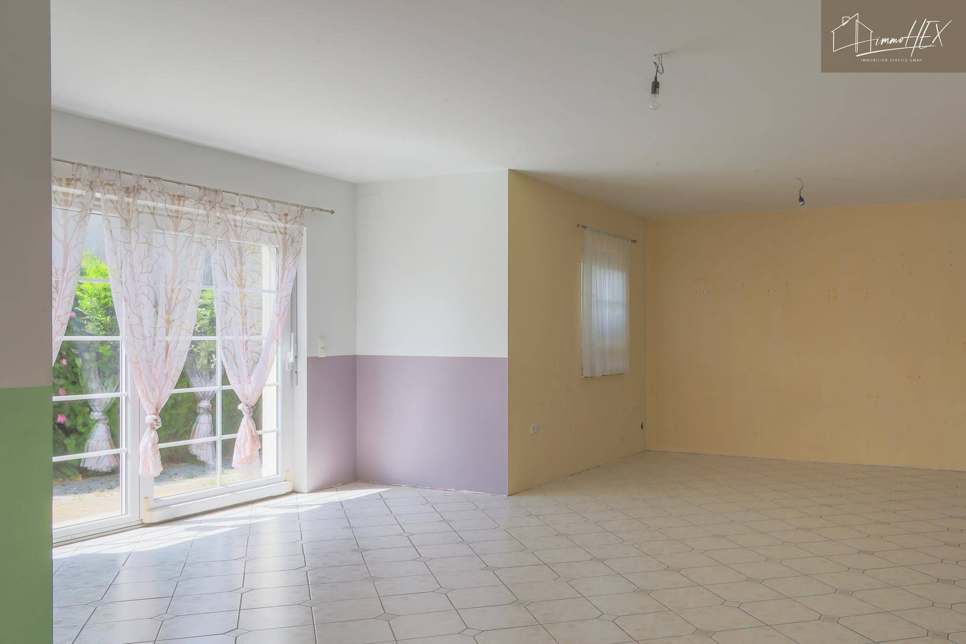 Heller Wohnbereich mit großen Terrassentüren, Fliesenboden und viel Platz für individuelle Gestaltung.