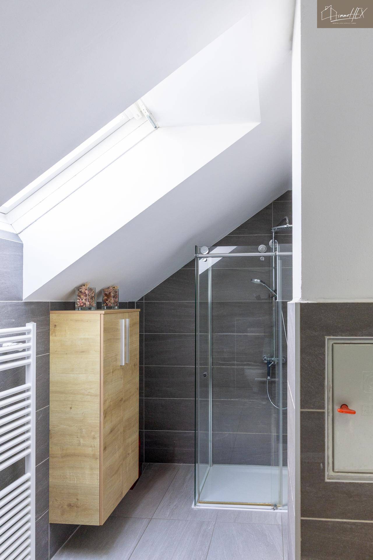 Helles Badezimmer mit Dachschräge, Duschkabine und Dachfenster.