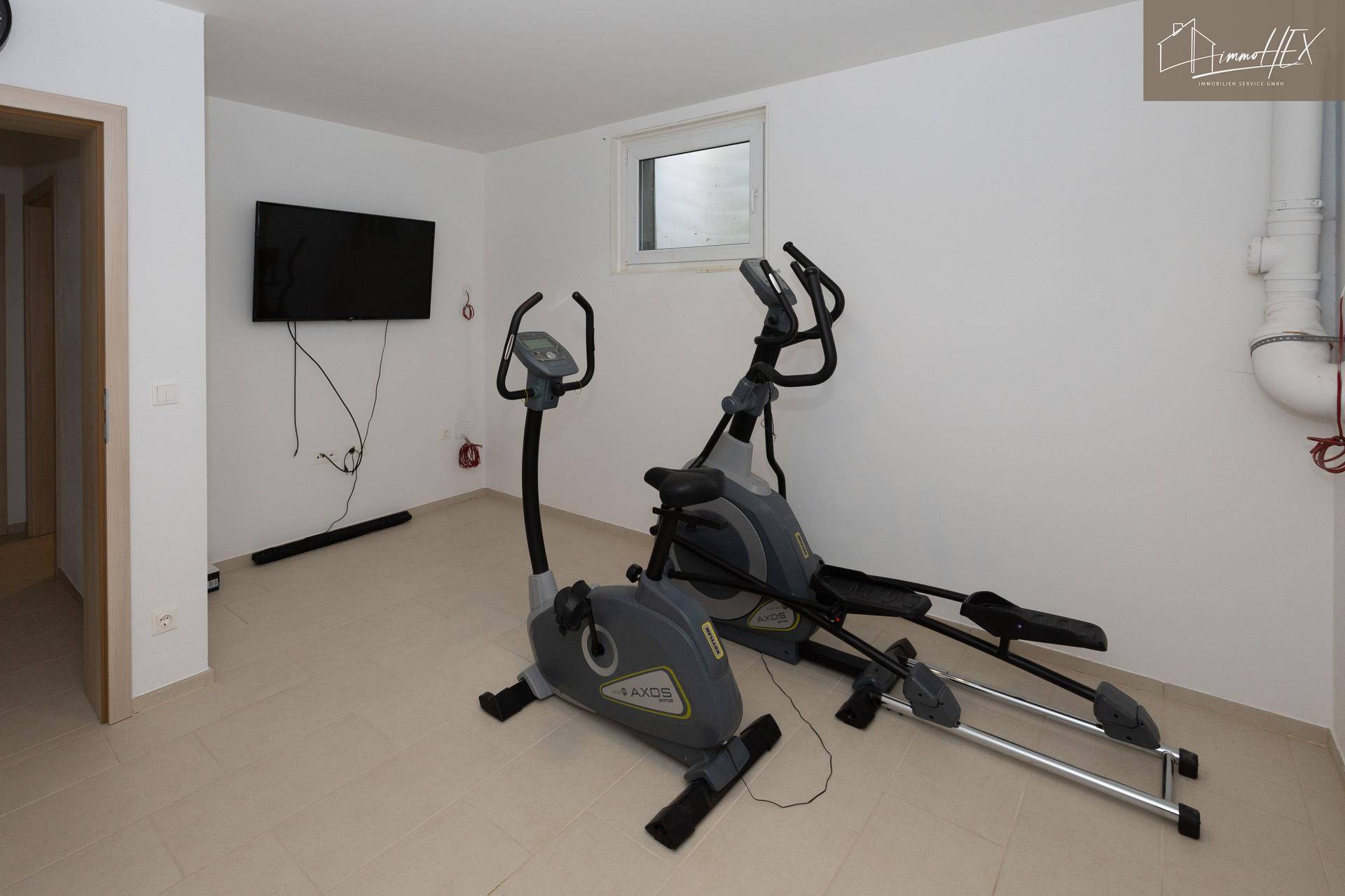 Fitnessraum mit zwei Trainingsgeräten und einem Wandfernseher, ideal für das Heimtraining.