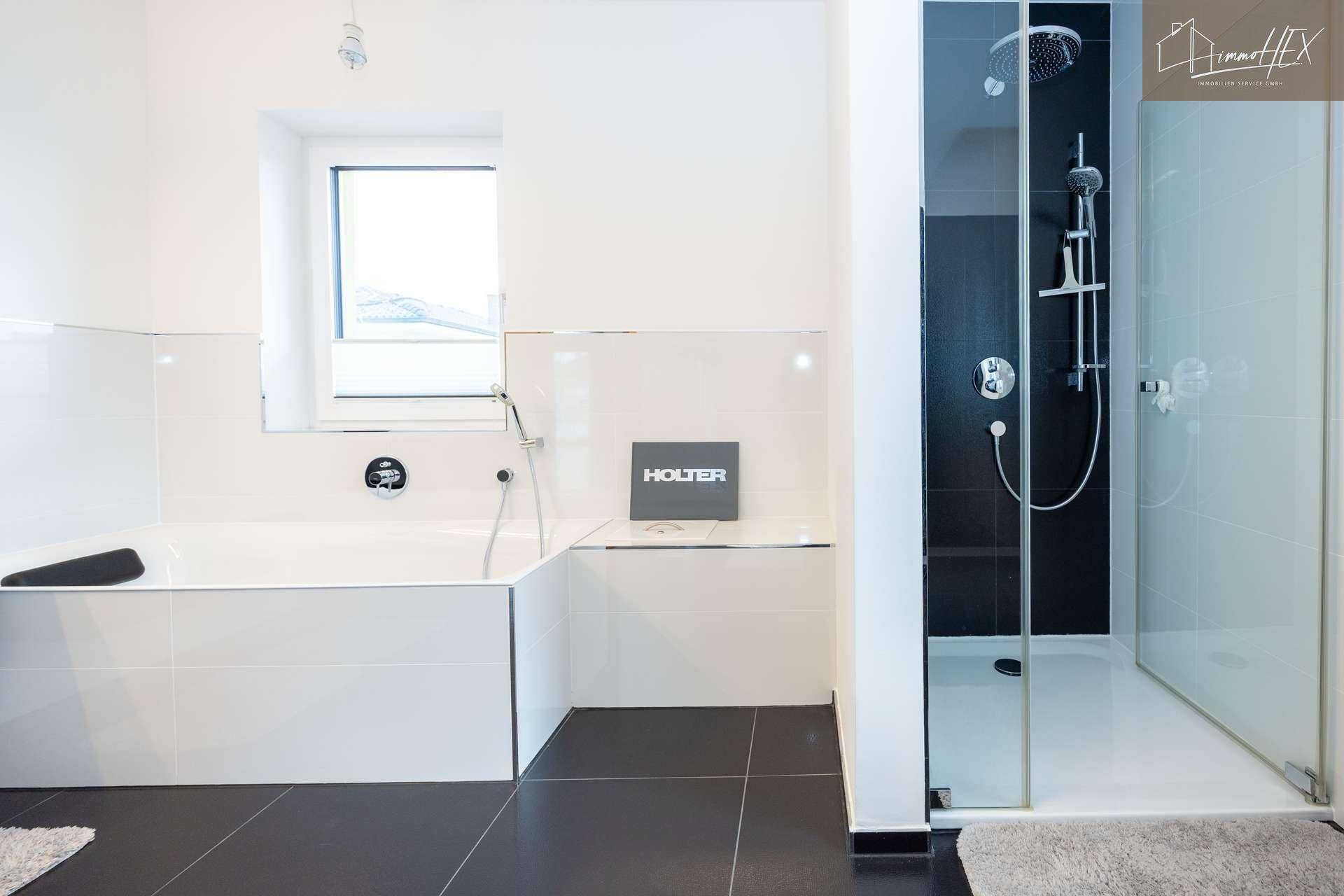Modernes Badezimmer mit Badewanne, begehbarer Dusche und dunklen Bodenfliesen.