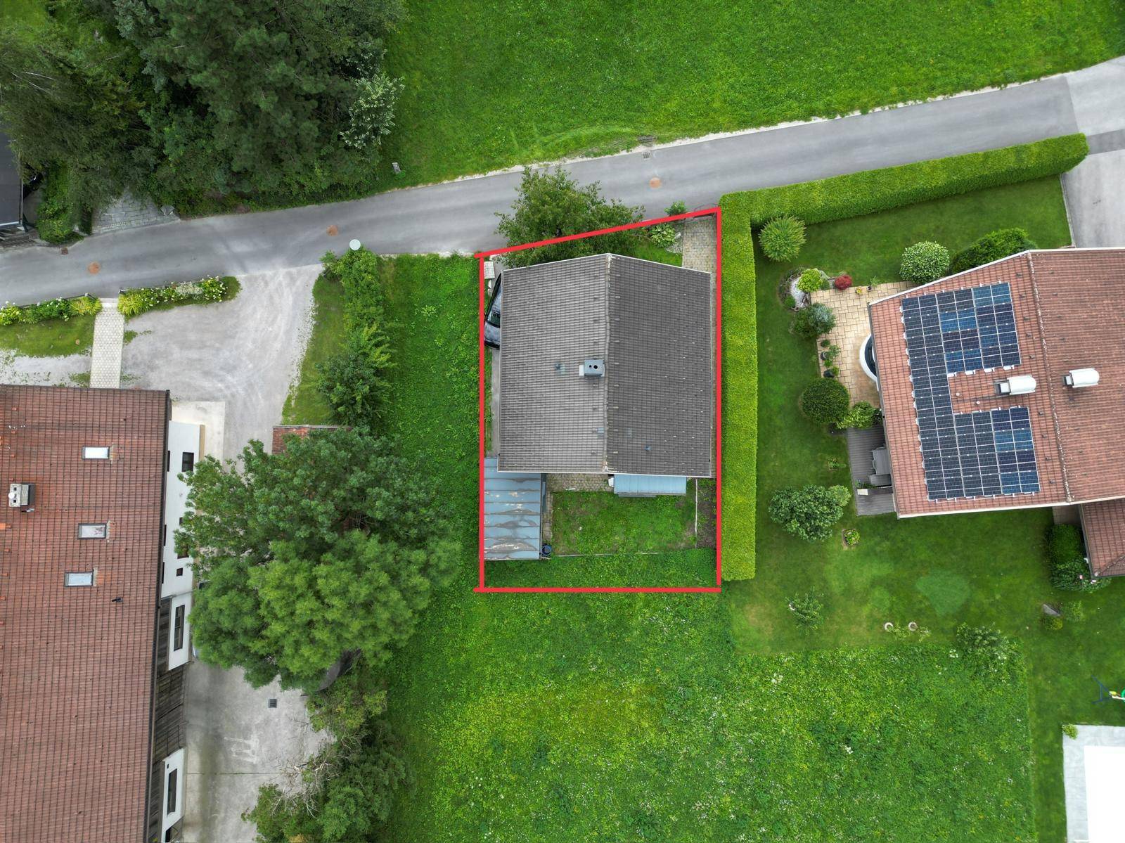 Vogelperspektive eines Hauses mit Grundstücksgrenze, umgeben von viel Grün und Nachbarhäusern.