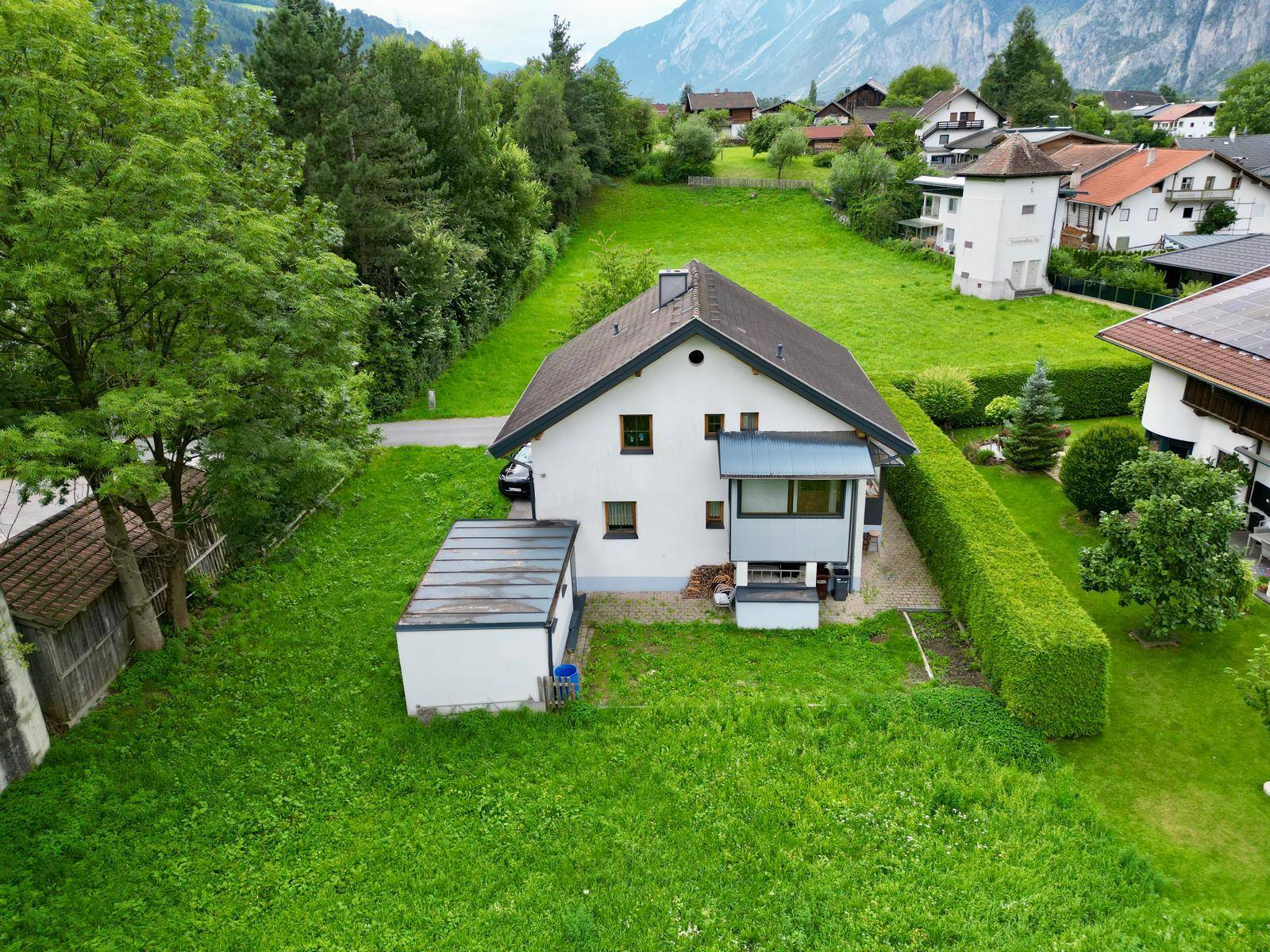 Freistehendes Haus mit weißer Fassade, Satteldach und großem Garten in ländlicher Umgebung.