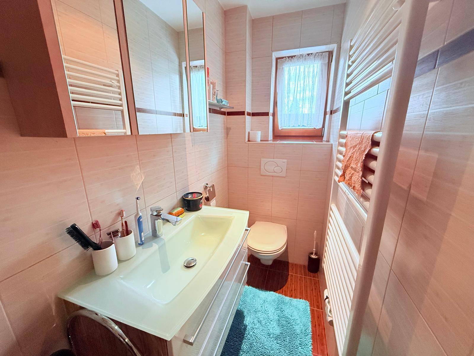 Kleines Badezimmer mit beigefarbenen Fliesen, Einzelwaschbecken und WC.