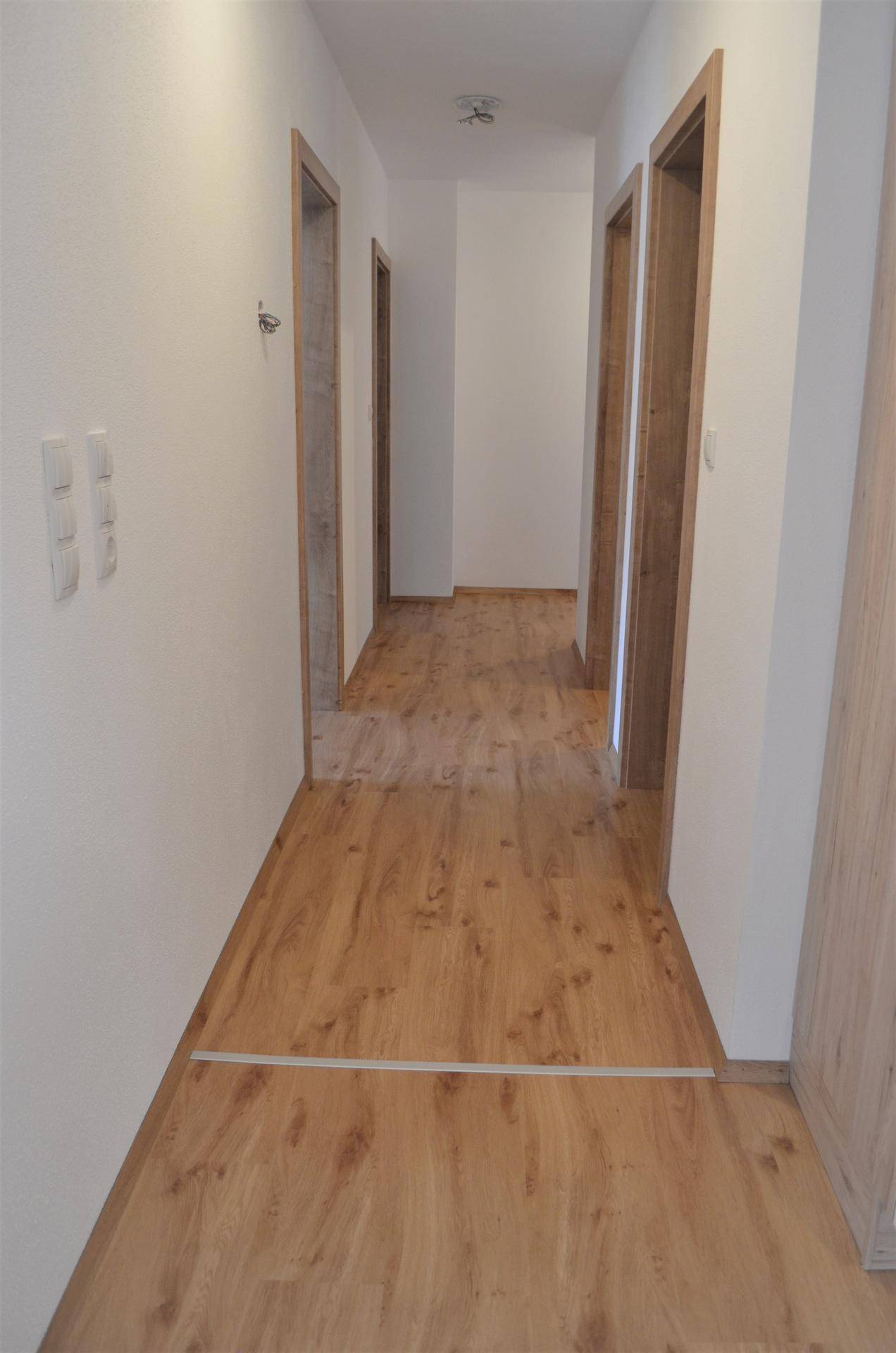 Langer, heller Flur mit mehreren Türen und durchgehendem Laminatboden.