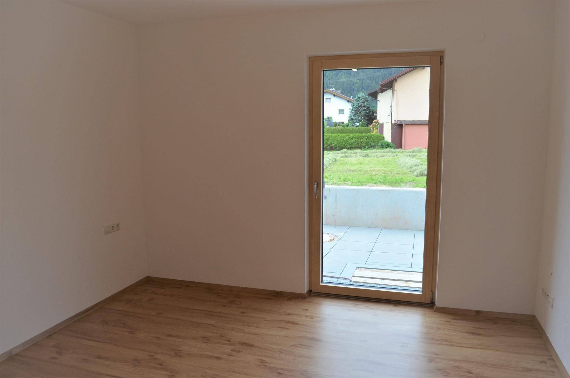 Kleiner Raum mit einer Tür, die zu einer Außenterrasse führt, und Laminatboden.