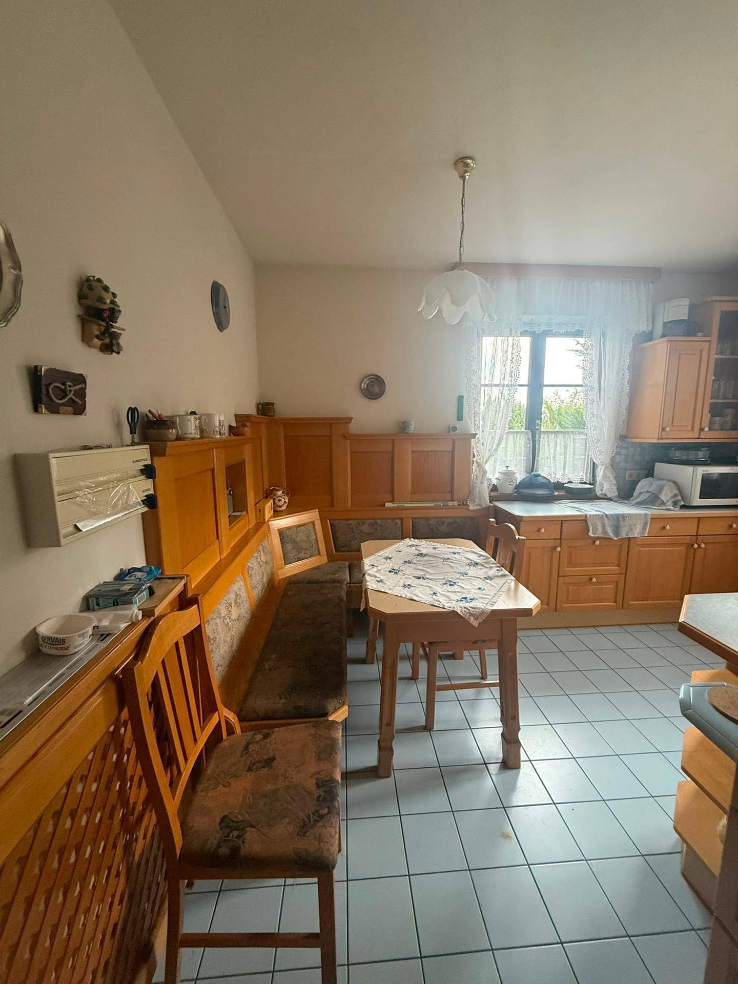 Gemütliche Wohnküche mit traditionellen Holzmöbeln, Essbereich und Blick ins Grüne durch das Fenster.