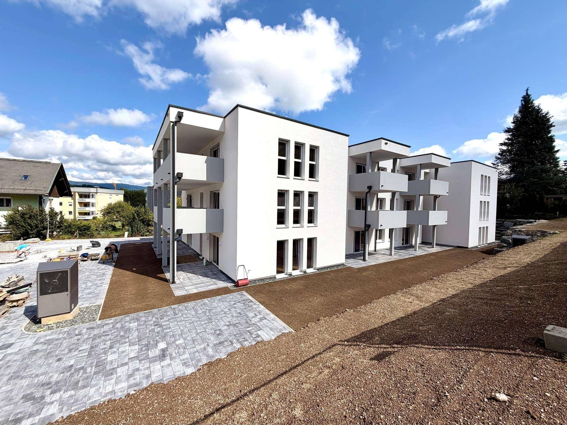 Neubau einer modernen Wohnanlage mit klaren Linien und Balkonen unter blauem Himmel.
