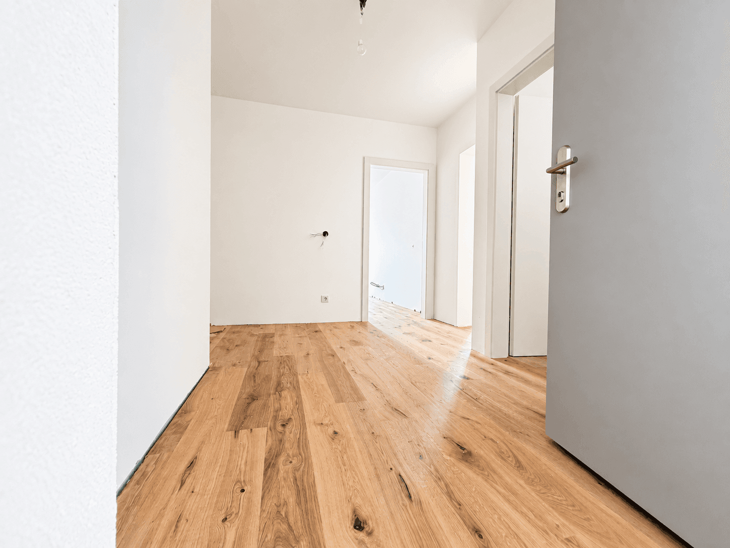 Heller Flur mit Holzboden und Zugang zu mehreren Zimmern, der viel Platz bietet.