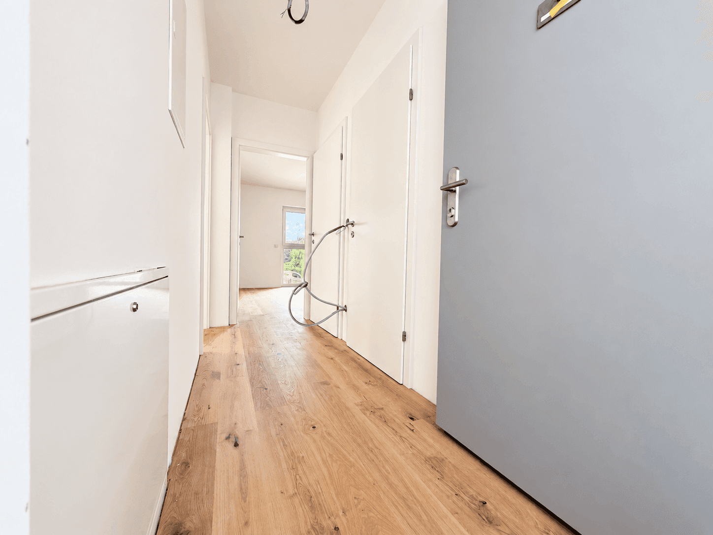 Heller Flur mit Holzboden und mehreren Türen, der verschiedene Räume der Wohnung verbindet.
