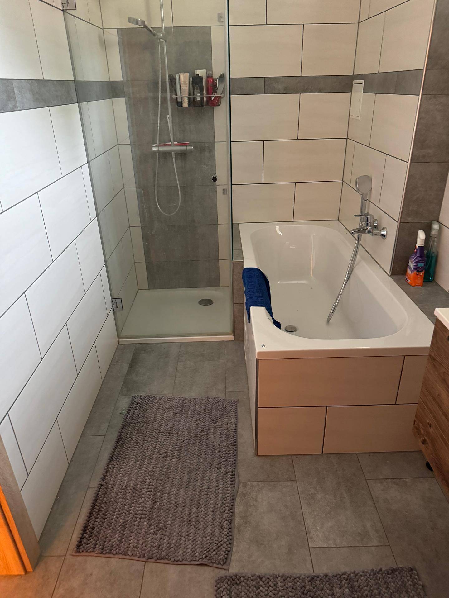 Badezimmer mit Duschkabine, Badewanne und modernen Fliesen.