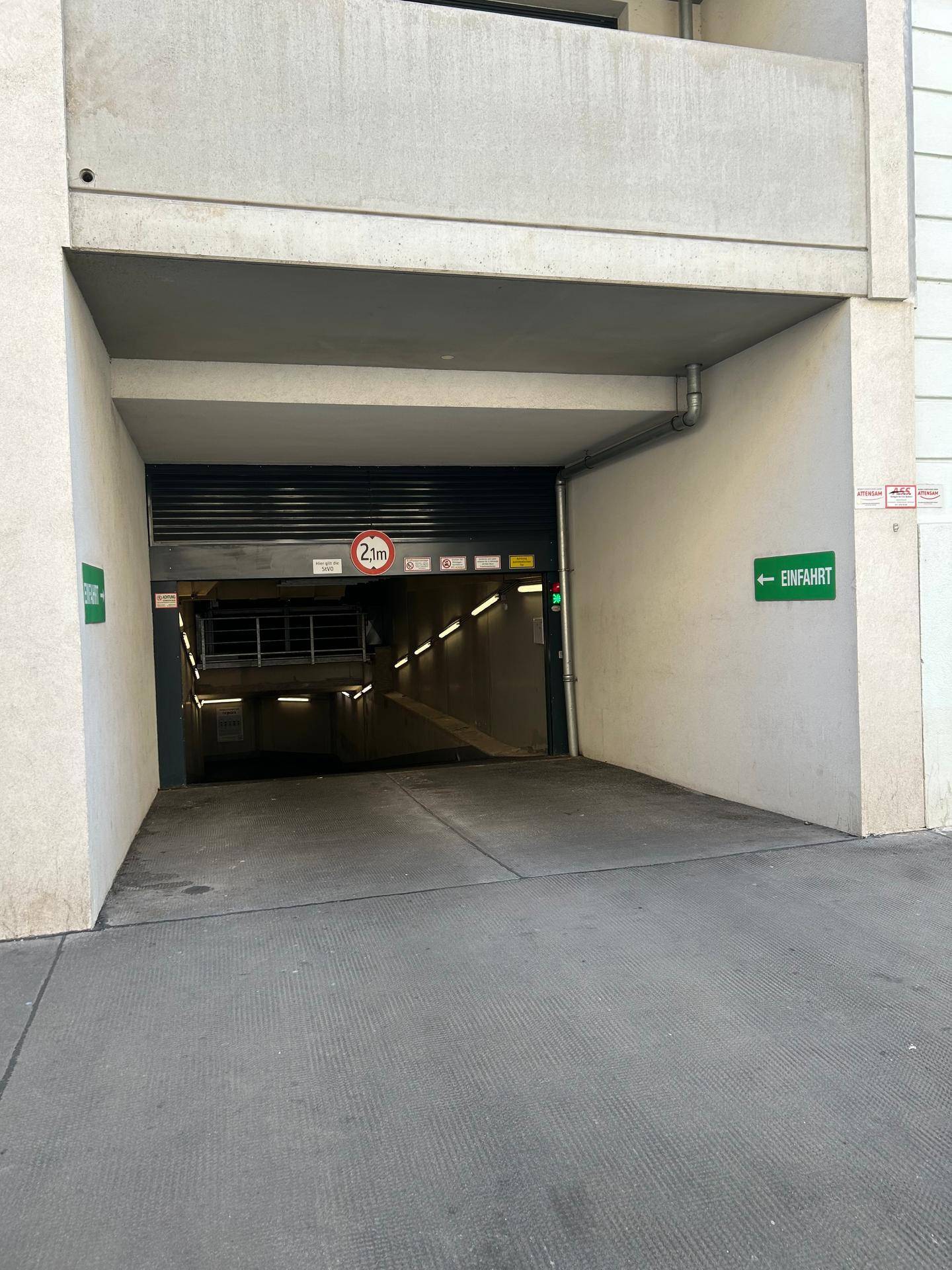 Einfahrt zur Tiefgarage mit Höhenbegrenzung und Hinweisschildern in einem modernen Gebäude.