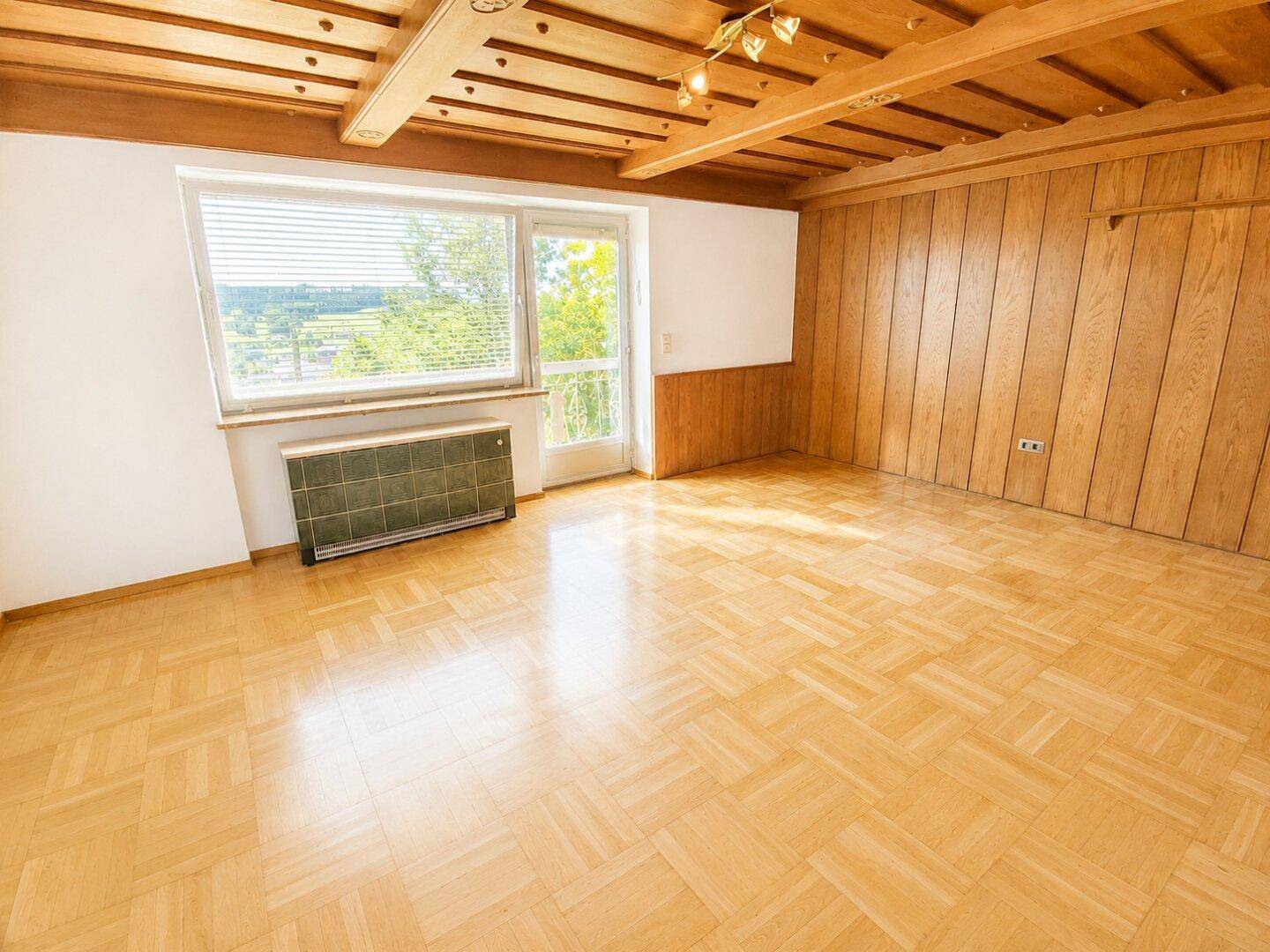 Heller Raum mit traditioneller Holzvertäfelung, Holzbalkendecke und Parkettboden.