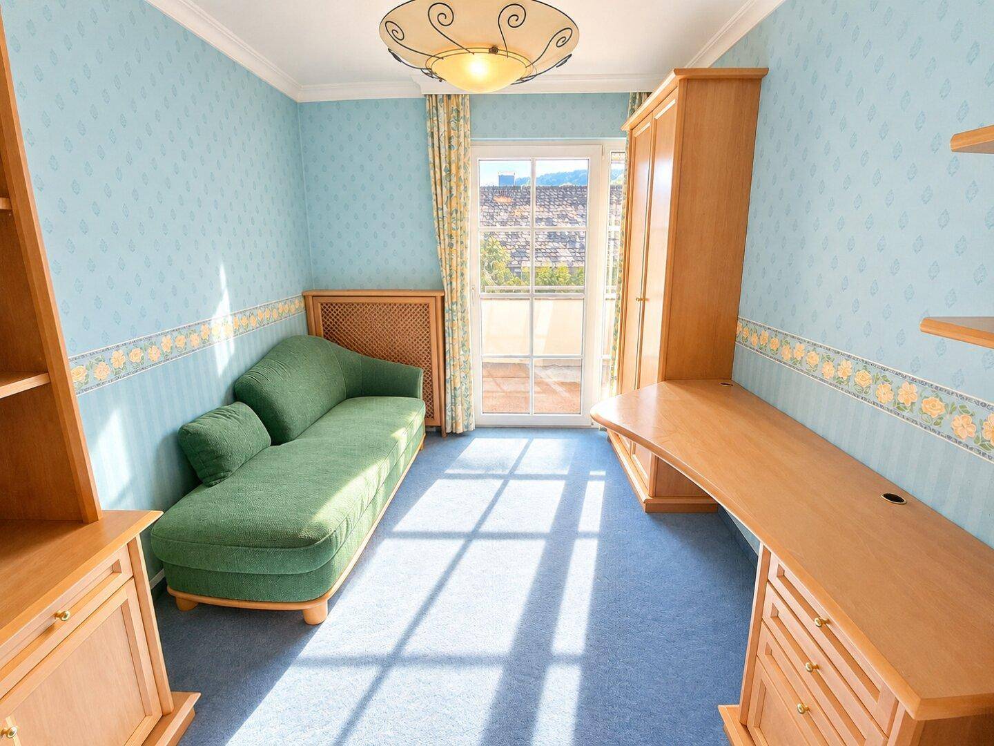 Funktionales Arbeitszimmer mit Schreibtisch, Tagesbett und Zugang zu einem kleinen Balkon.