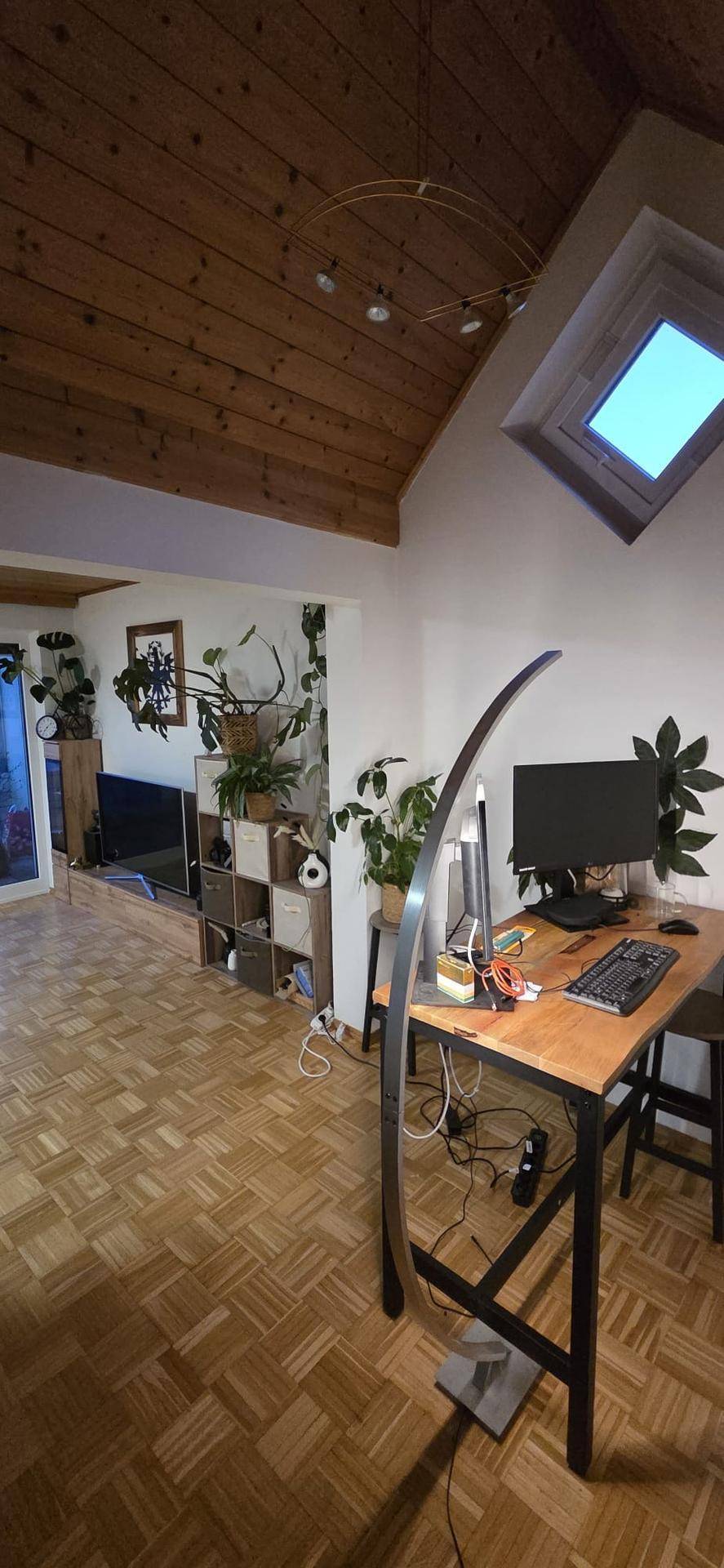 Heller Arbeitsbereich mit Holzdecke, Parkettboden und Dachfenster für natürliches Licht.