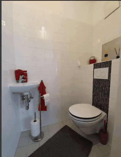 Kleines Gäste-WC mit Wand-WC, Waschbecken und modernen Fliesenakzenten.