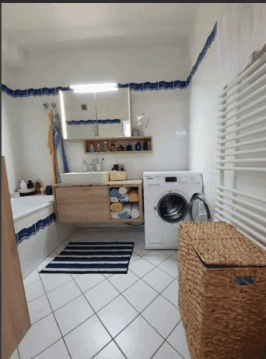 Helles Badezimmer mit Badewanne, Waschmaschine und beheiztem Handtuchhalter.