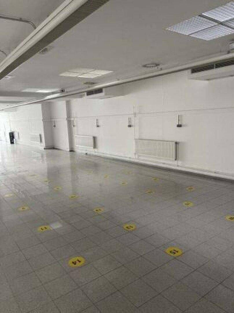 Weitläufiger Gewerberaum mit glänzenden Fliesen, weißen Wänden und integrierter Deckenbeleuchtung.