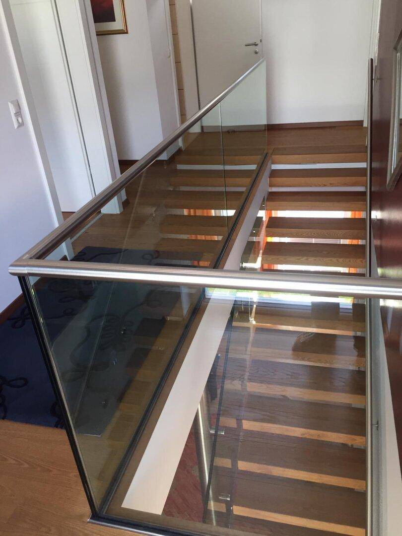 Moderne Treppe mit Holzstufen und eleganter Glasbrüstung, die das obere Stockwerk verbindet.