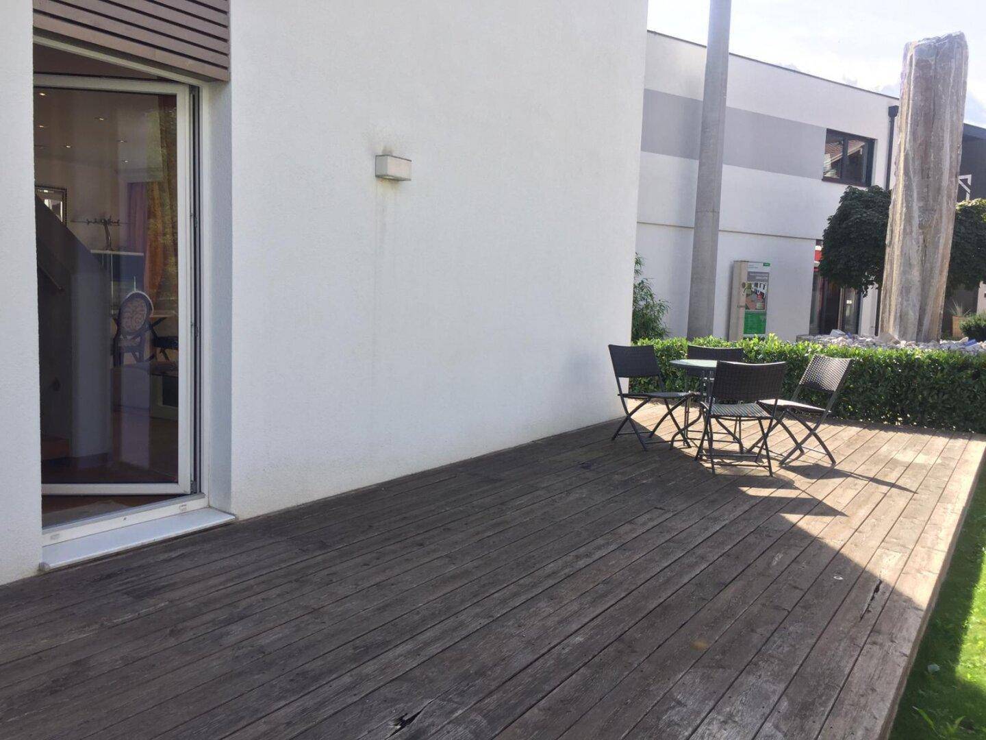 Holzterrasse mit Gartentisch und Stühlen, ideal für entspannte Stunden im Freien.