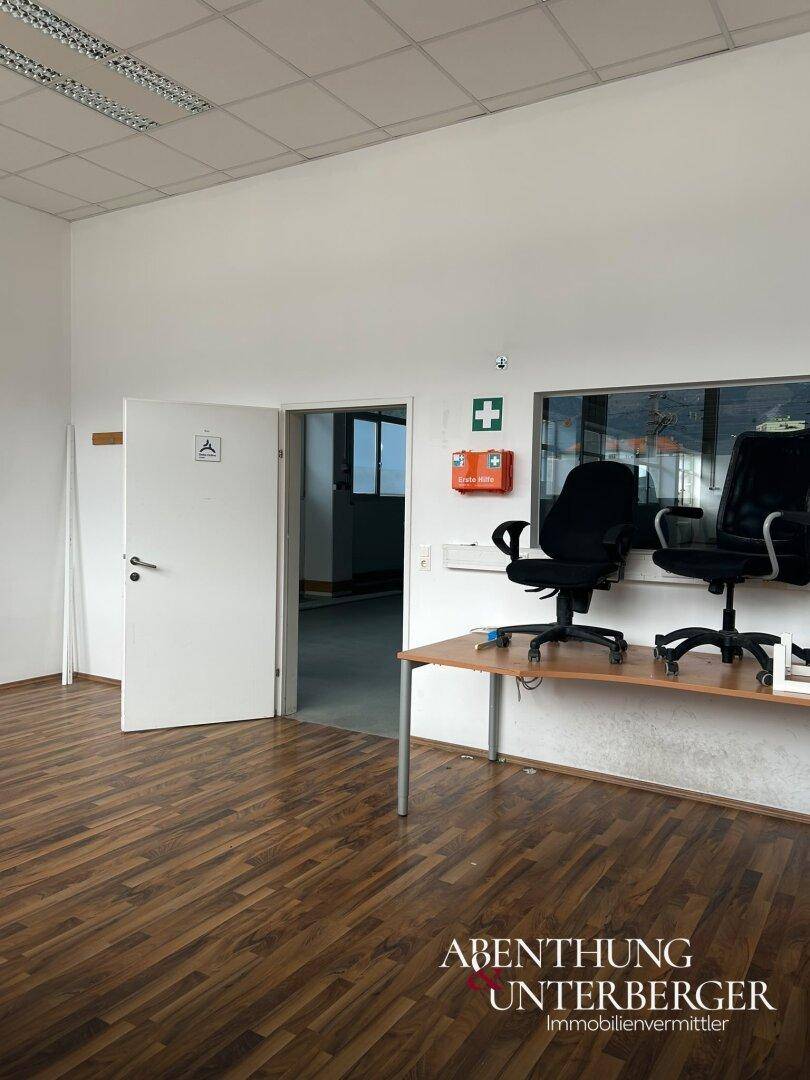 Büroraum mit Laminatboden, offenem Durchgang und einem Schreibtisch mit zwei Bürostühlen.