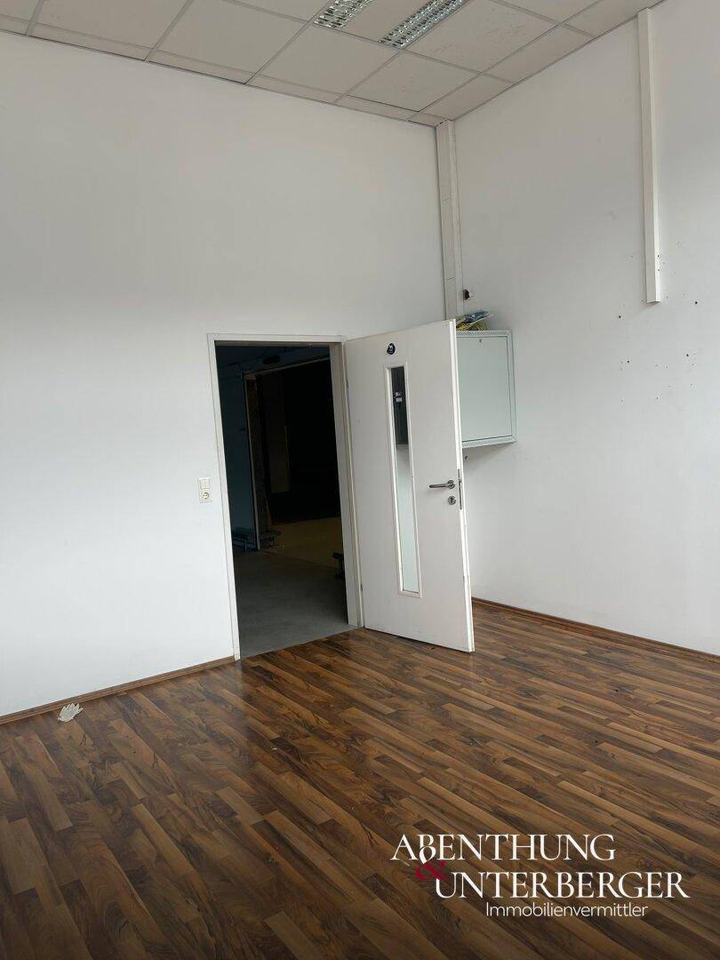 Innenraum eines Büros mit hellem Laminatboden und weiß gestrichenen Wänden, bereit zur Einrichtung.